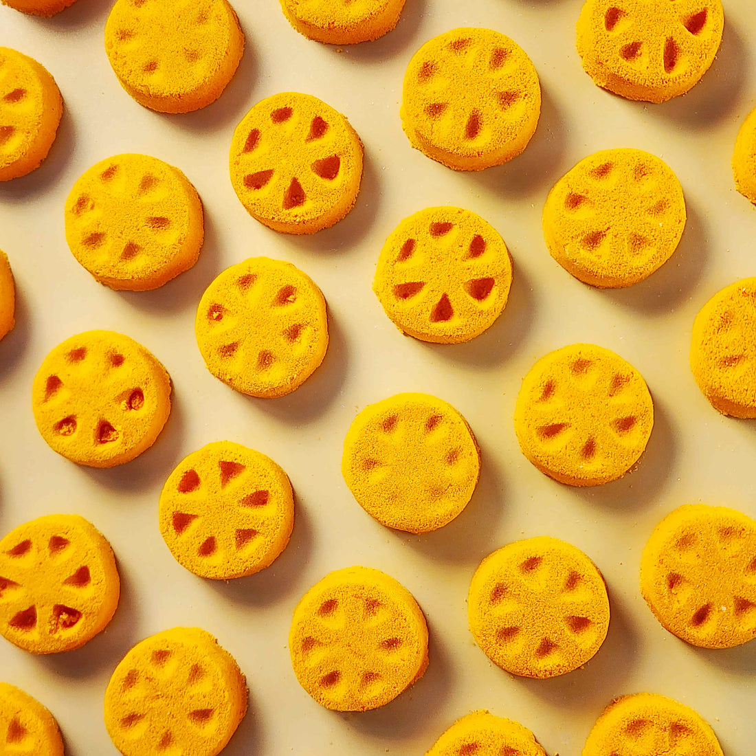 Orange citrus-slice miniature bath bombs arranged on a pale background