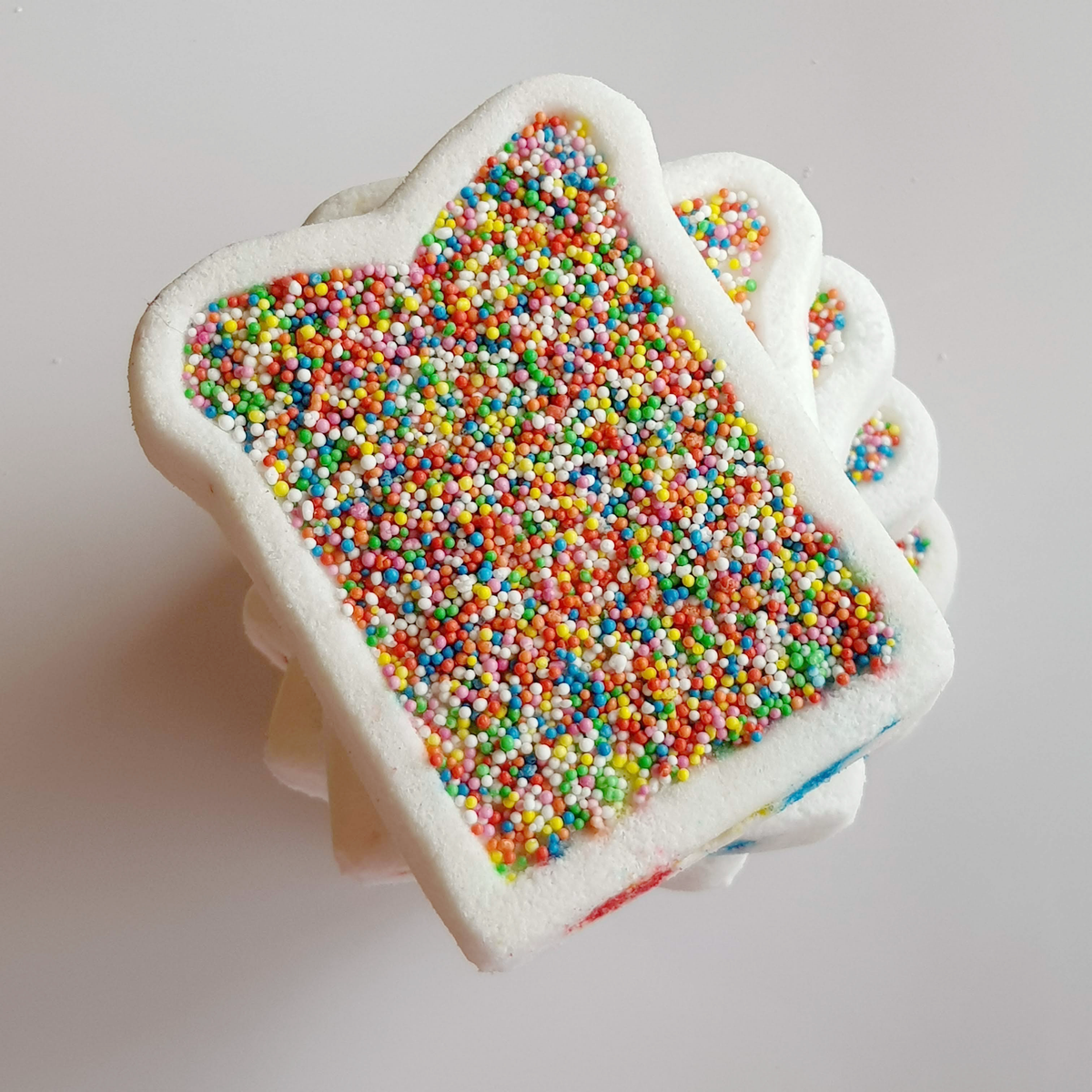 White fairy bread bath bombs covered with rainbow sprinkles