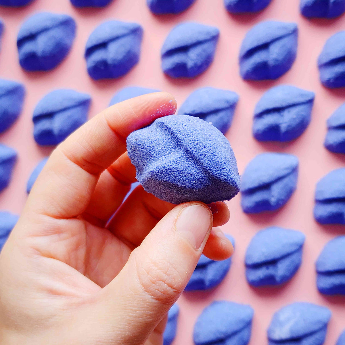 Hand holding a purple lip-shaped Lavender mini bath bomb