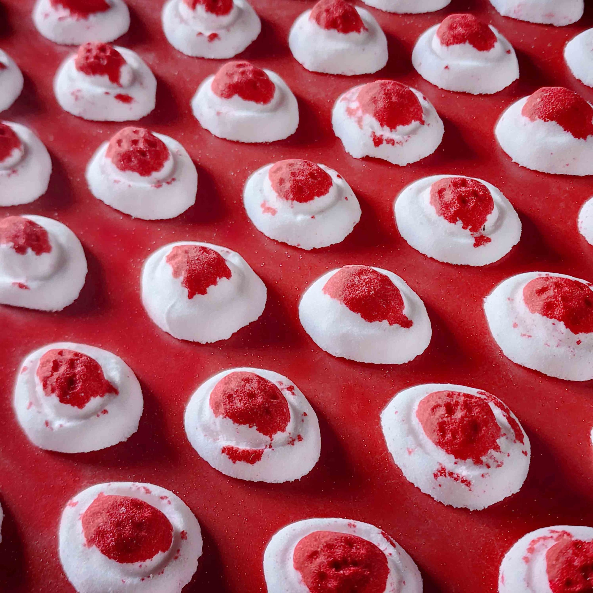 Mini red and white bath bomb inspired by the berry and cream soft lolly from the classic australian party mix