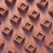 Chocolate square mini bath bombs arranged on a pink background