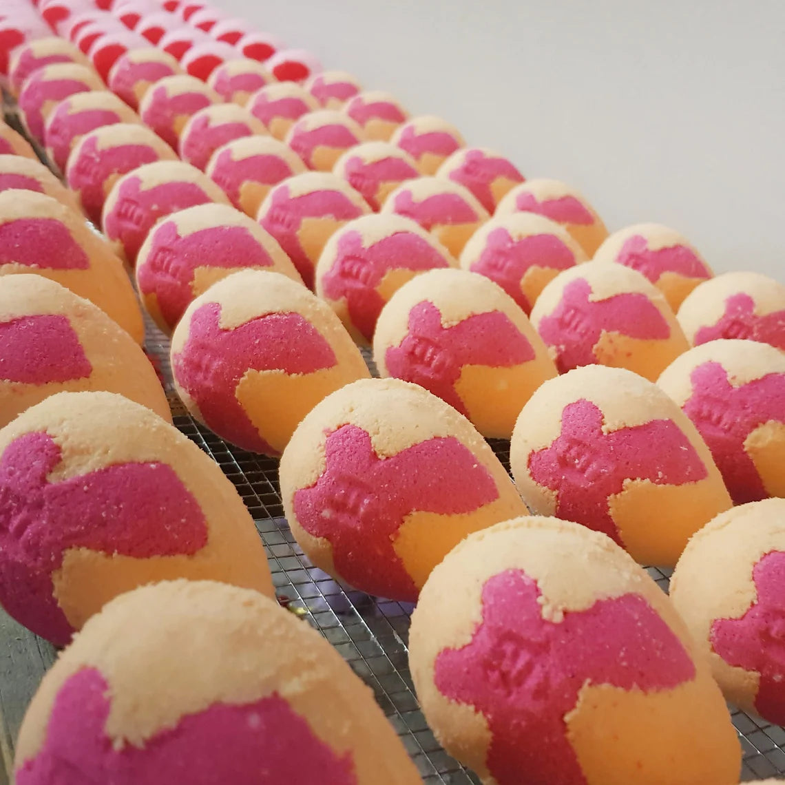 peach egg shaped bath bomb with a bright pink butterfly in the middle