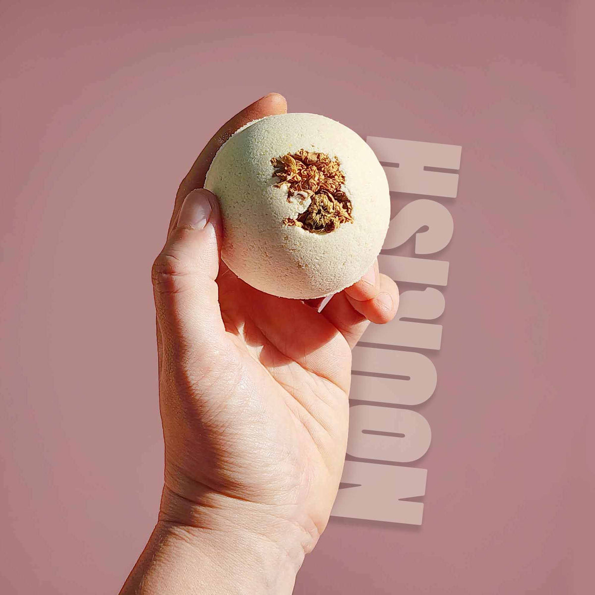Hand holding the cream Nourish aromatherapy bath bomb