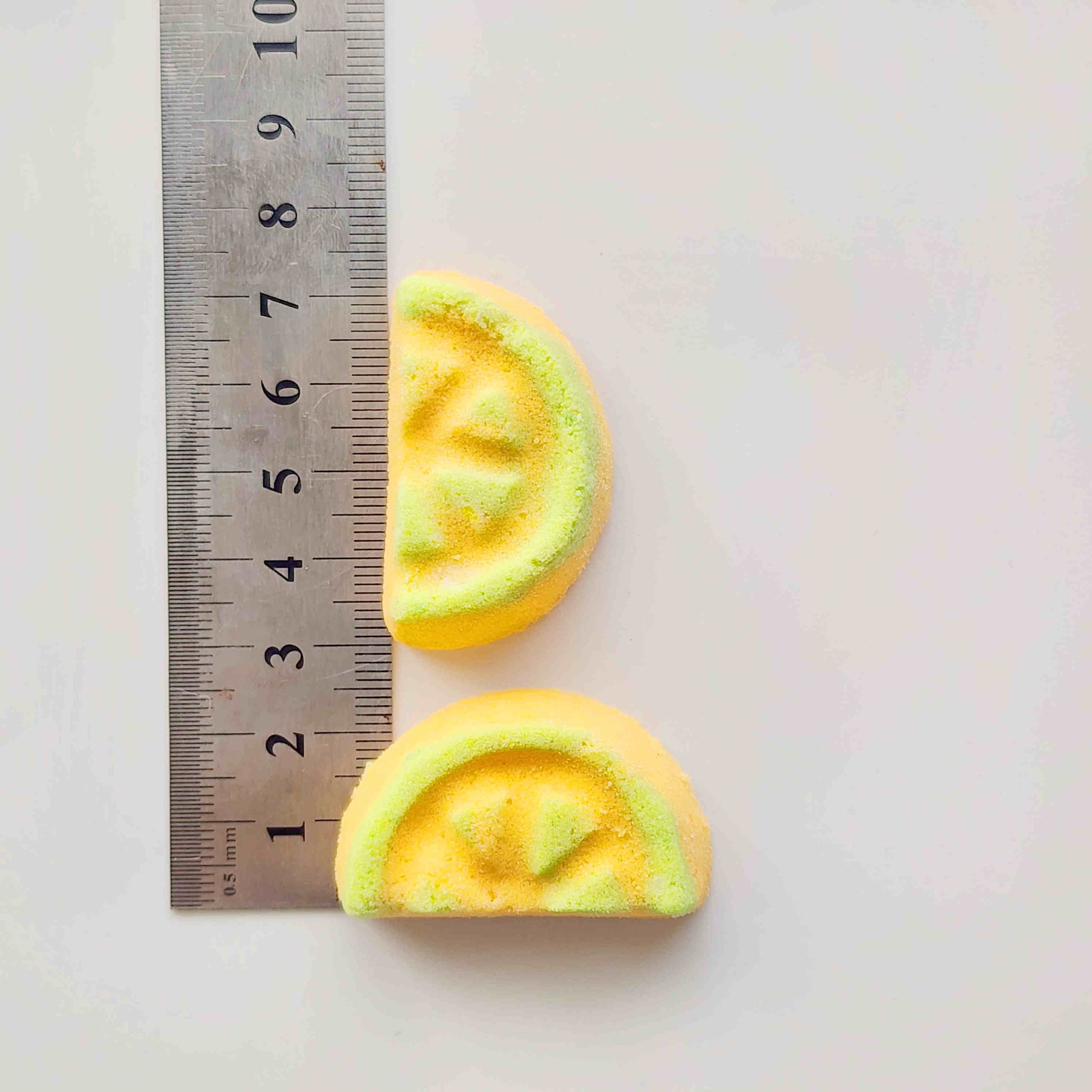 Two honeydew mini bath bombs measured beside a ruler