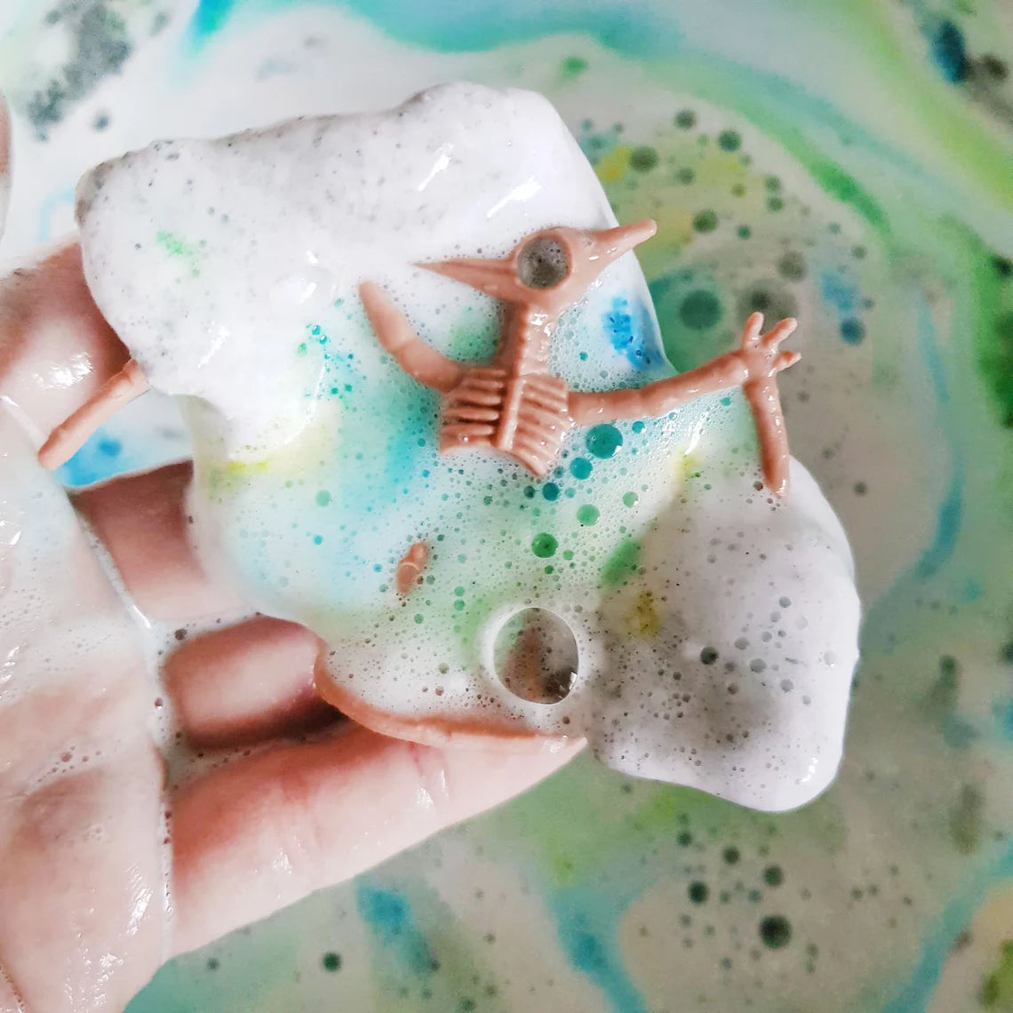 dinosaur fossil toy being revealed in a bath bomb in the bath