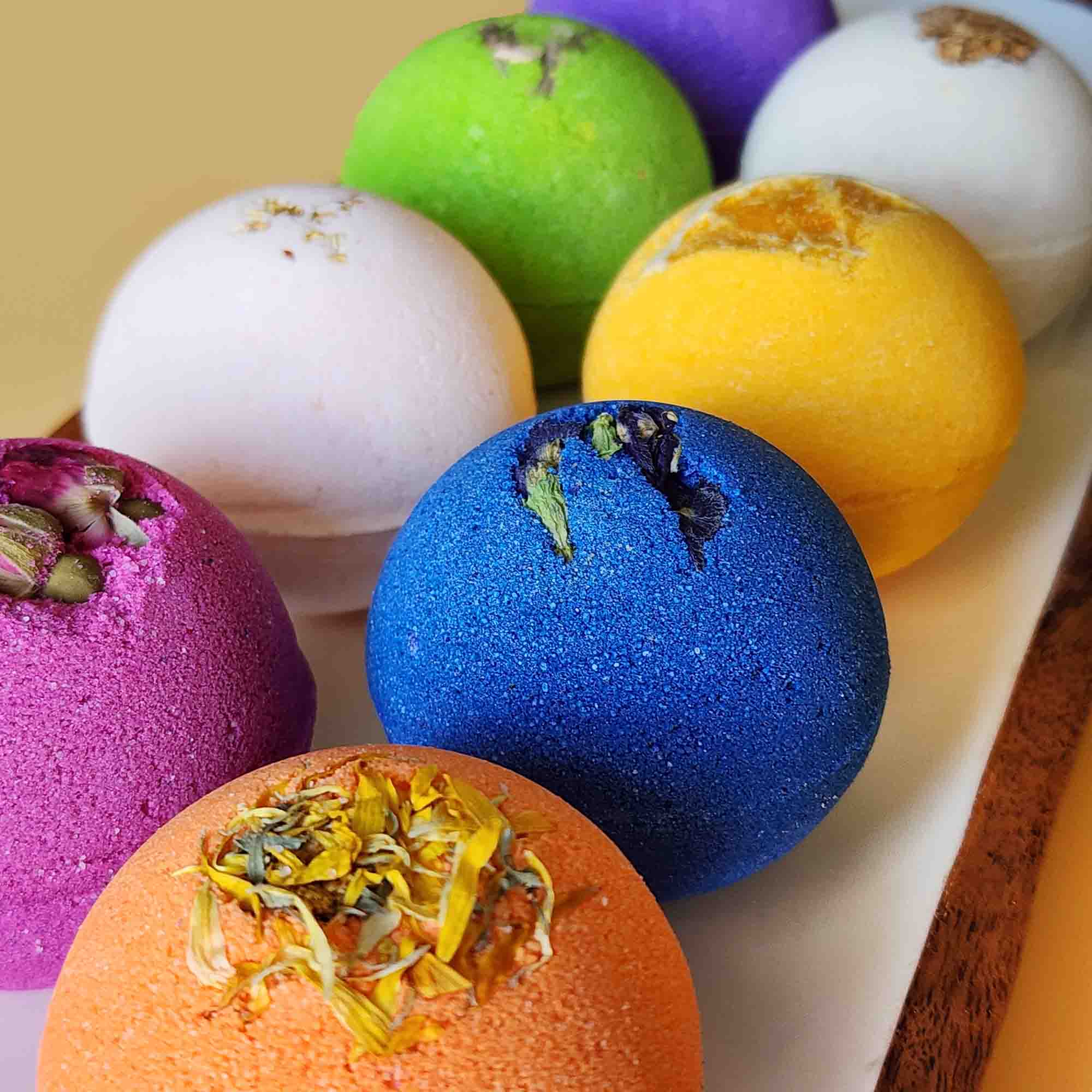 Close-up of colorful Essential 8 bath bombs topped with dried botanicals