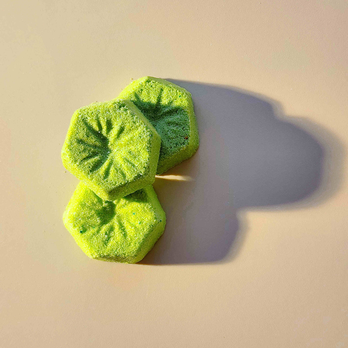 Three green kiwi mini bath bombs casting a long shadow