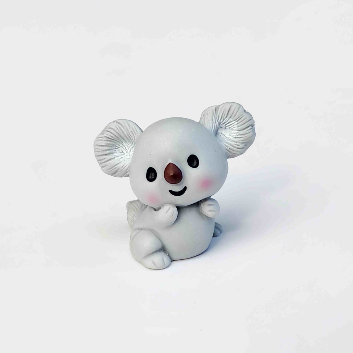 cute grey koala figurine sitting on a white background