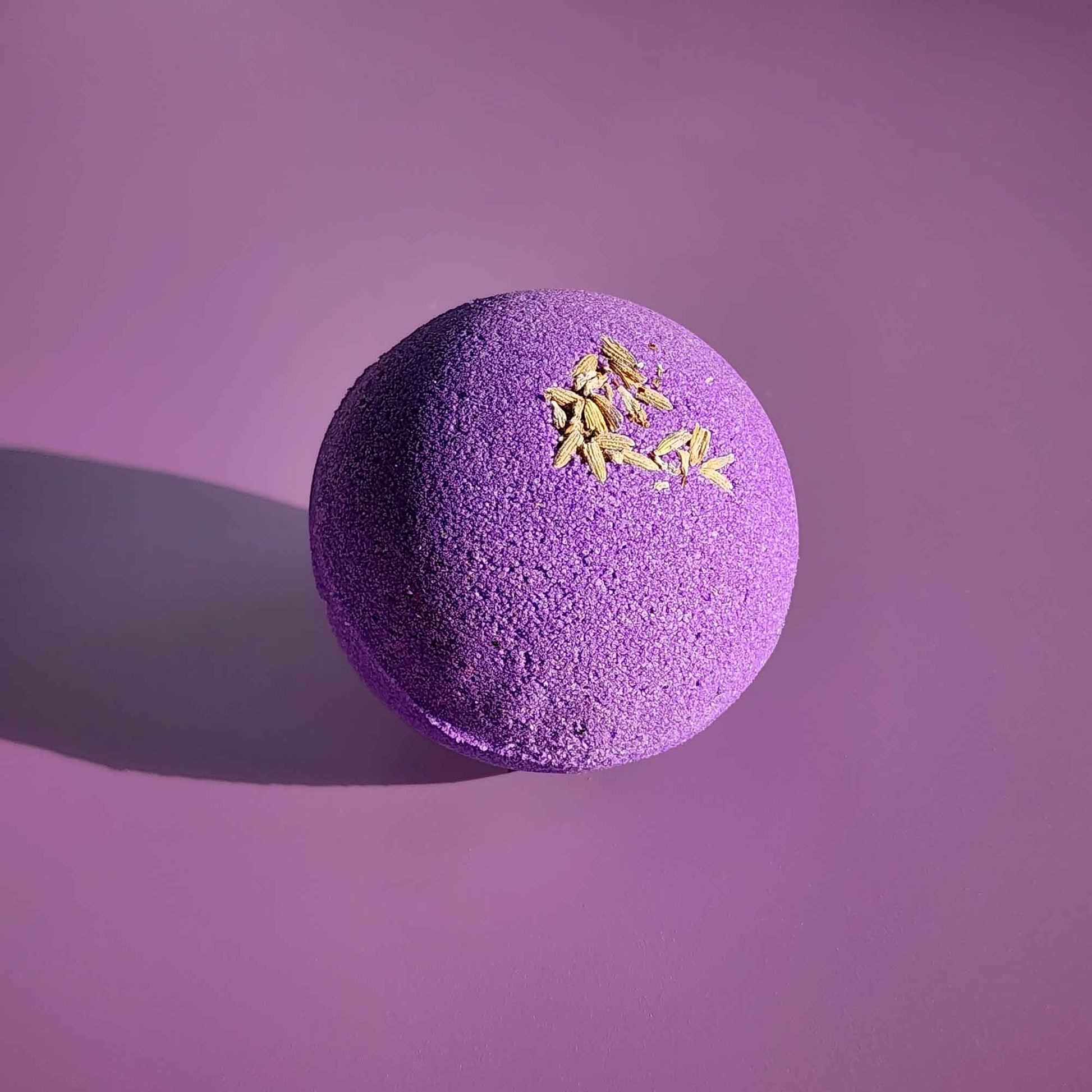 Single purple Relax bath bomb with dried lavender on a violet background