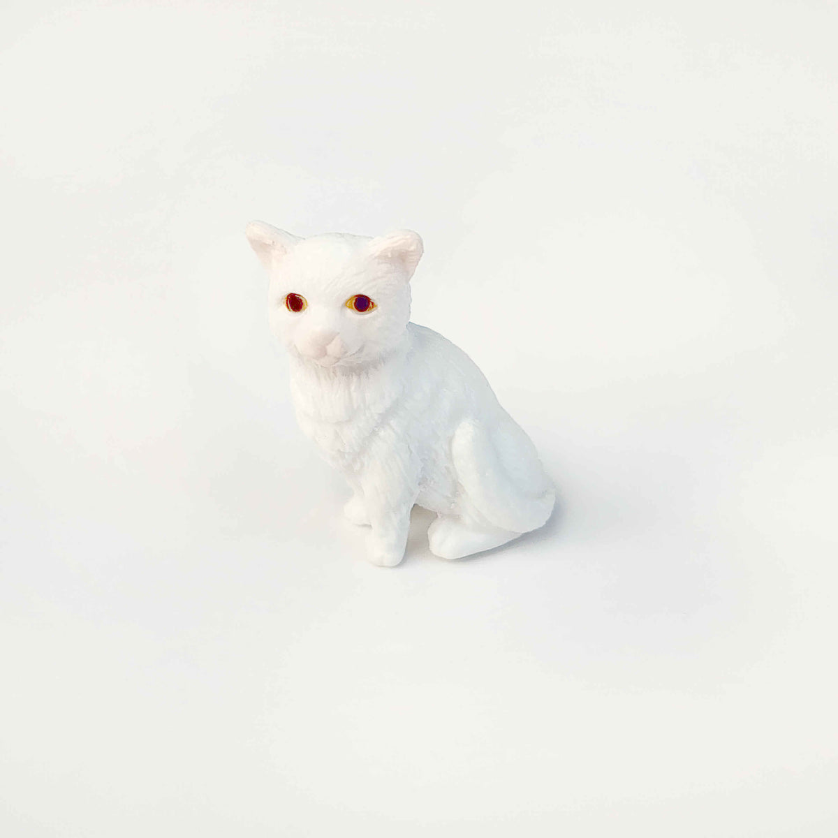 White pvc cat figurine sitting upright on a qhite background