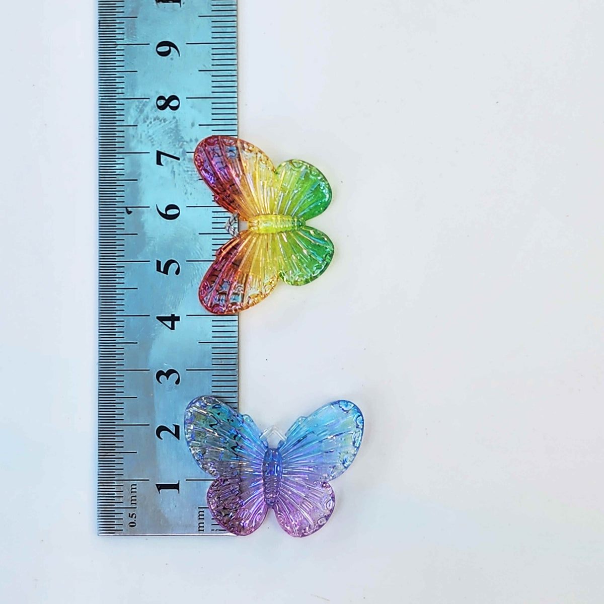 measurements for transparent butterfly charms against a steel ruler
