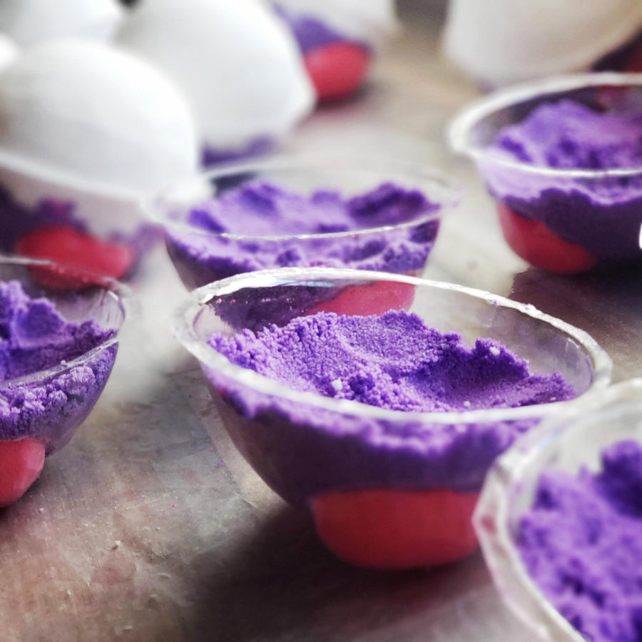 Purple Master Ball bath bomb mixture pressed into molds in the Fuzzbom studio