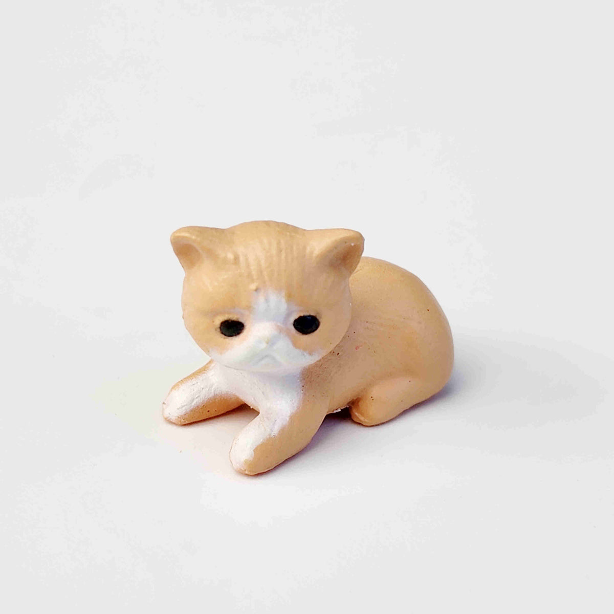 small tan coloured PVC cat figurine on a white background