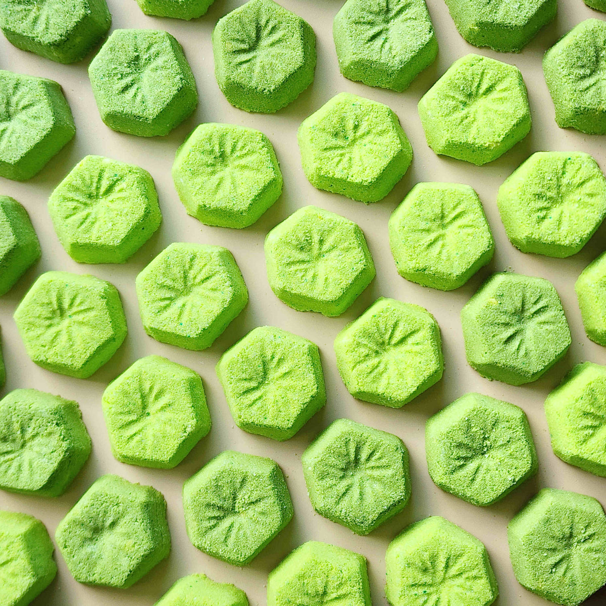Green kiwi-slice mini bath bombs arranged in rows