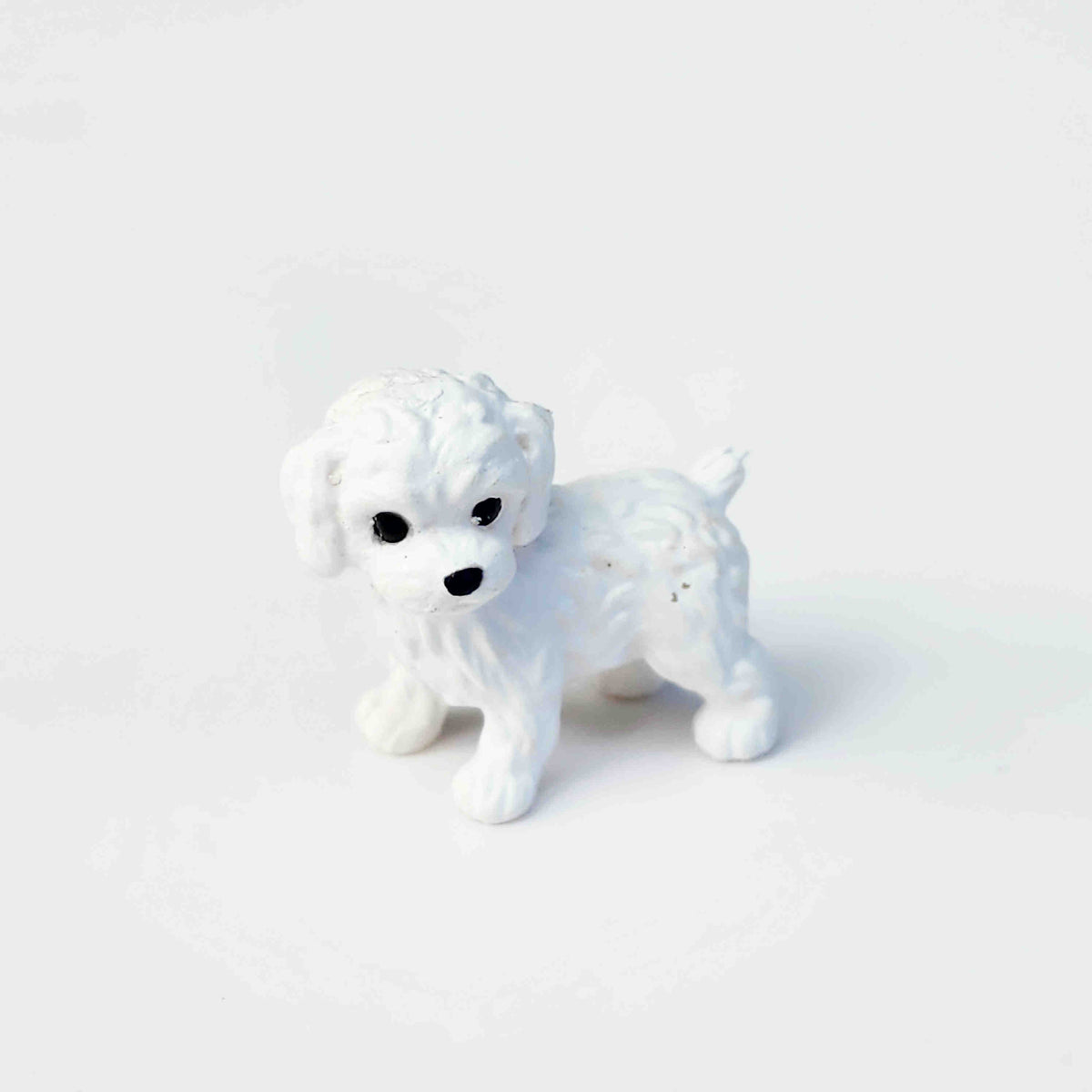 White puppy dog figurine placed on a plain white background