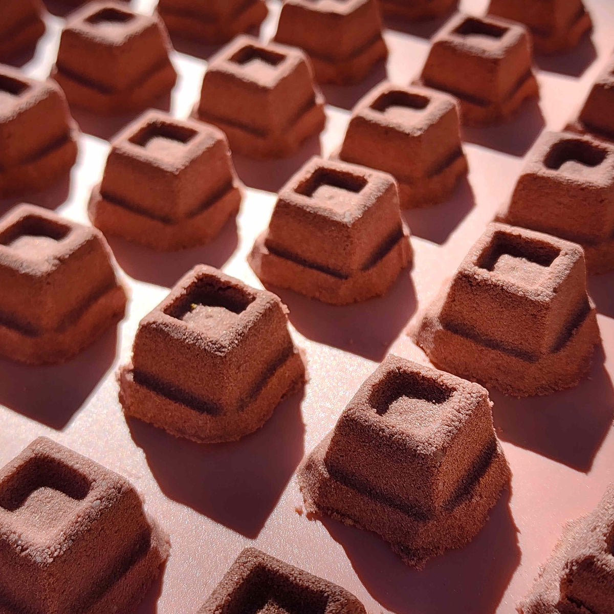 mini chocolate bath bombs shaped like cubes of chocolate on a plain brown background