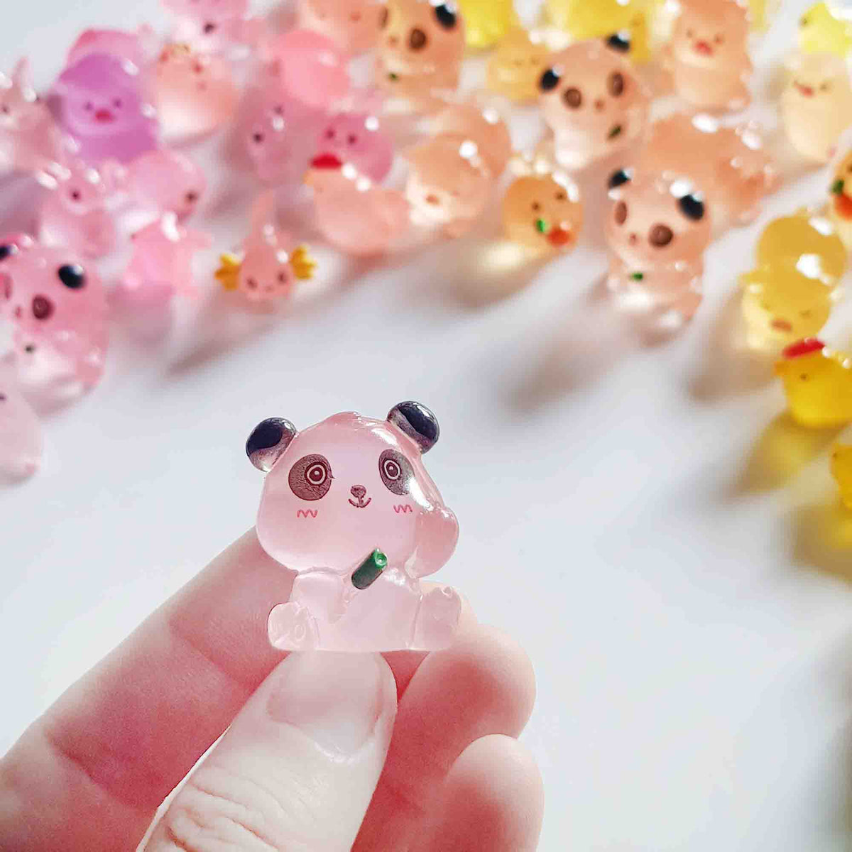 Tiny translucent panda fairy garden toy held between two fingers