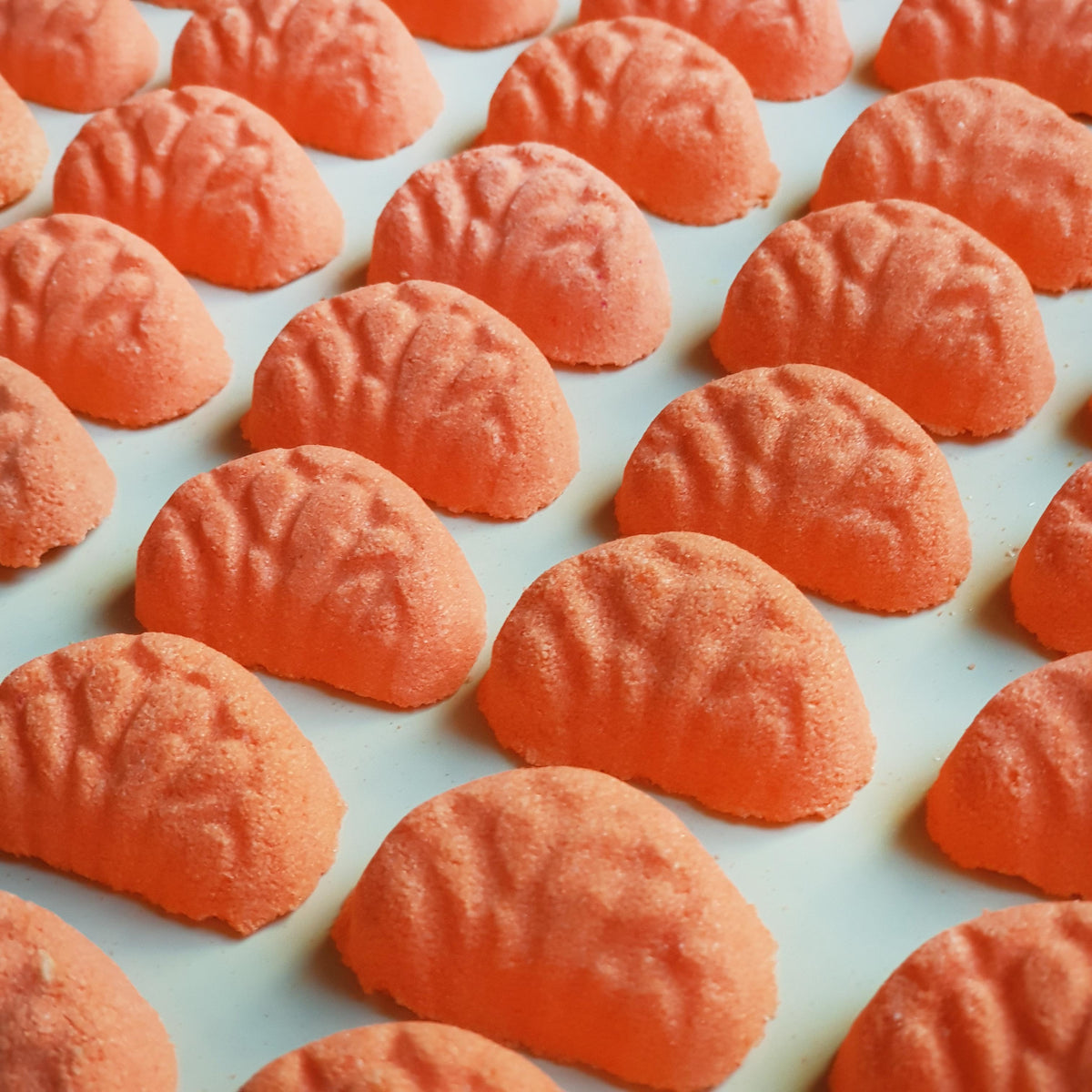 Miniature vibrant orange coloured mandarin bath bombs shaped as mini mandarin slices