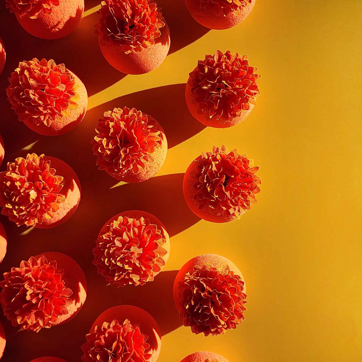 Warm light highlighting textured orange bath bombs topped with detailed calendula blooms