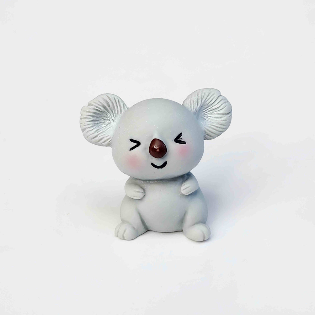 cute grey koala figurine sitting on a white background
