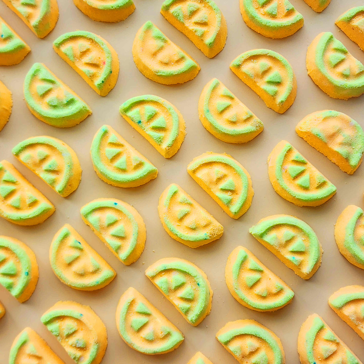 Yellow and green honeydew-slice mini bath bombs arranged in rows