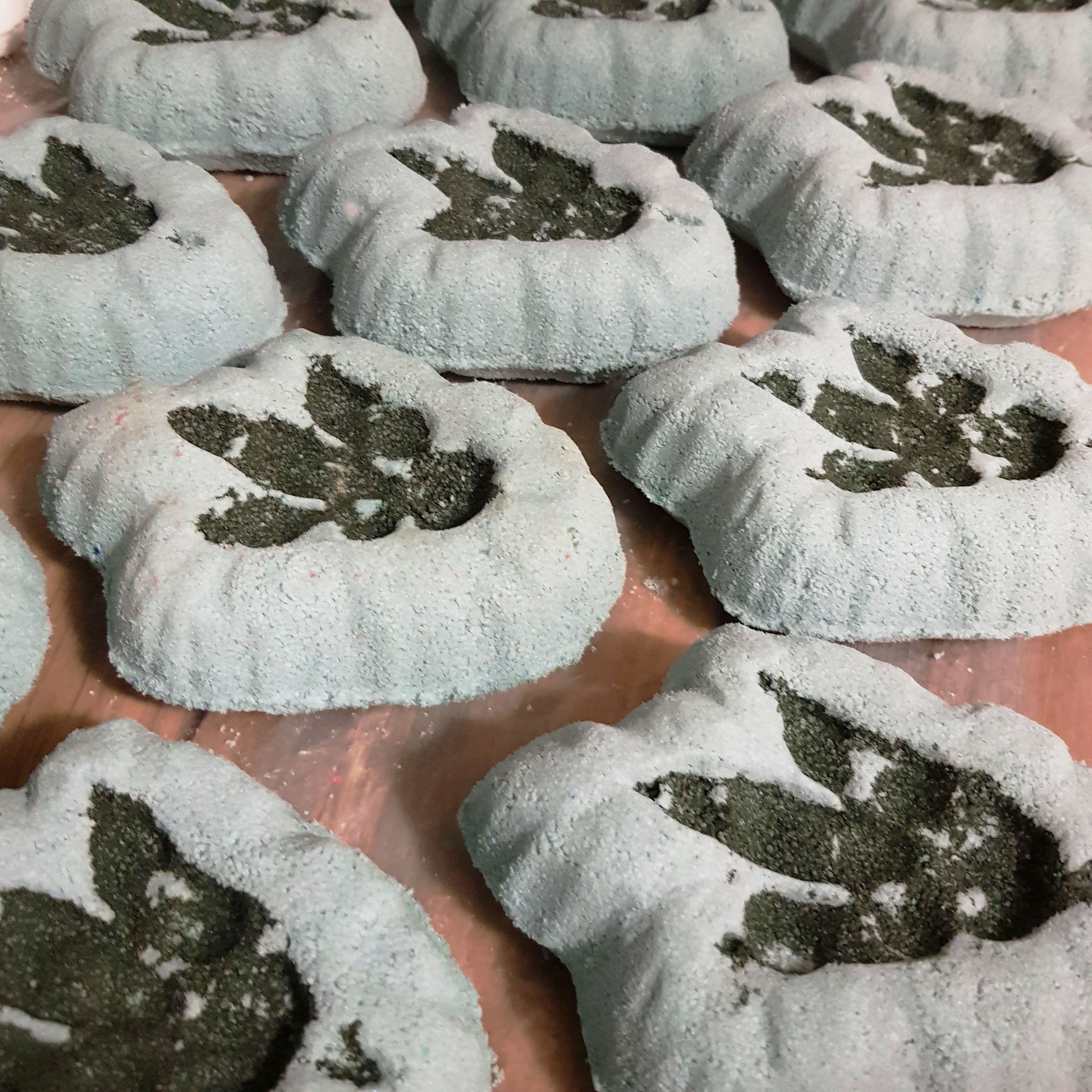 Grey bath bomb shaped like a dinosaur fossil with a dark dino footprint on it