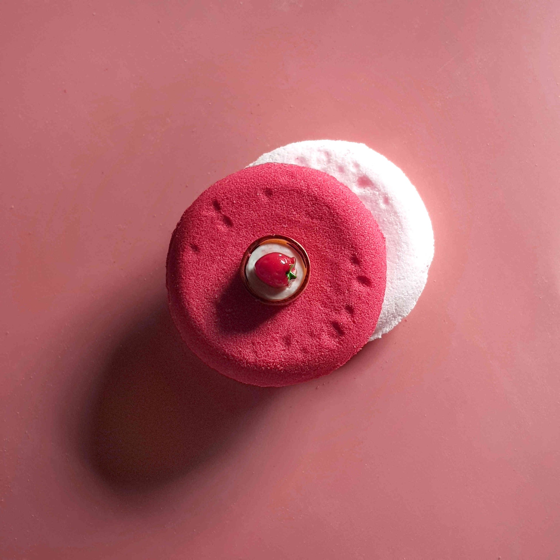 Flat disc shaped bath bomb stacked and placed on a plain pink background