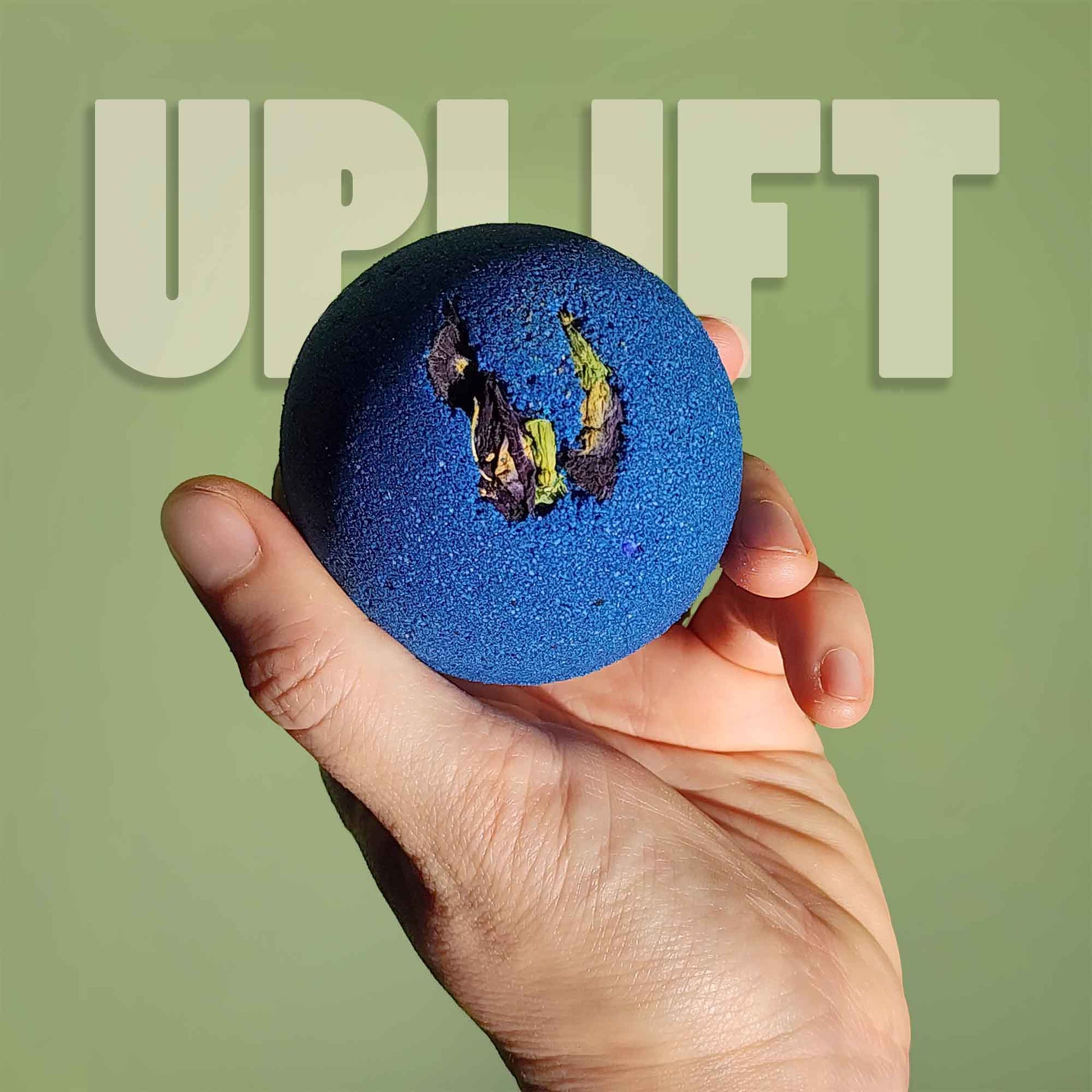 Hand holding the blue Uplift aromatherapy bath bomb