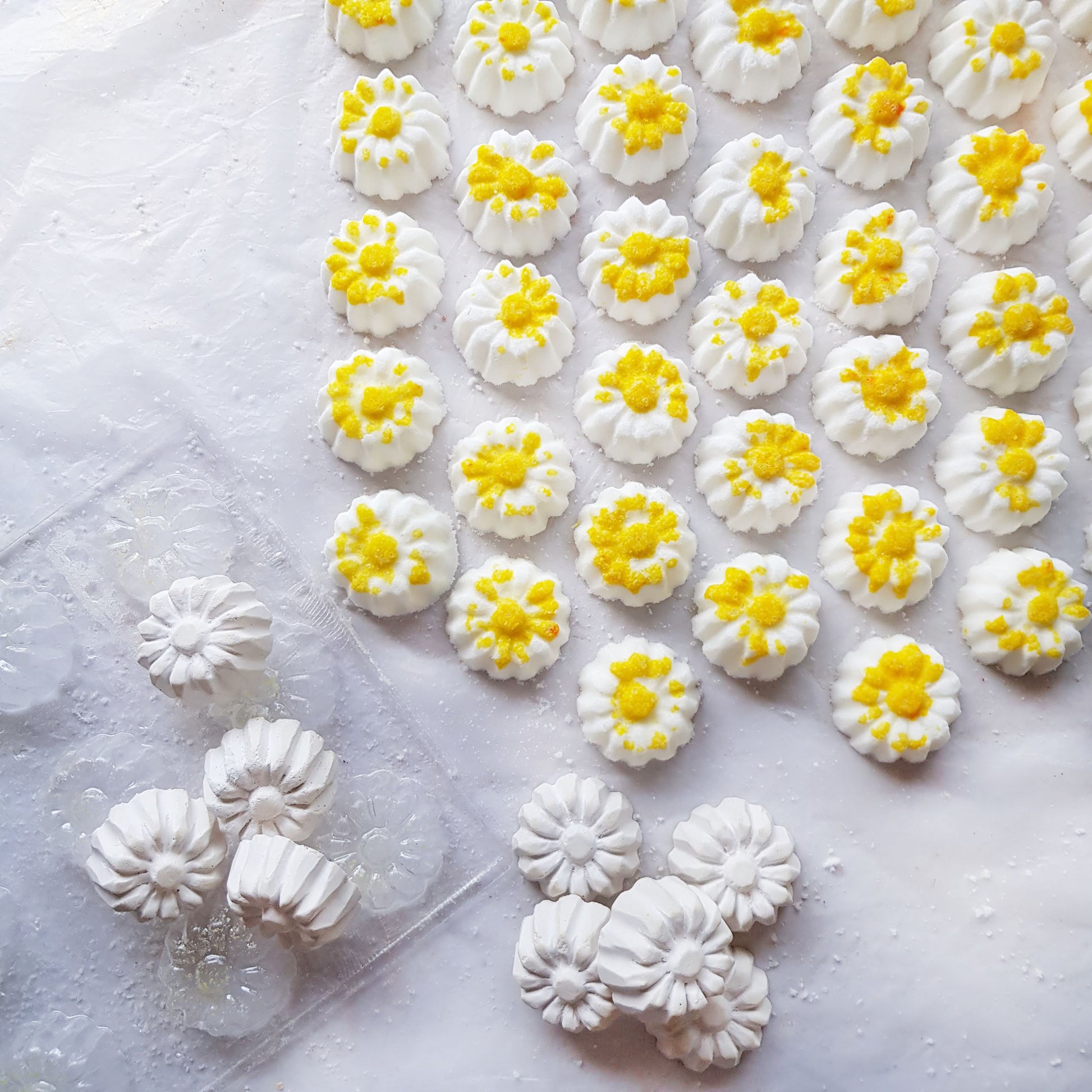 chamomile shaped mini bath bombs with a white base and yellow detail on a neutral plain background