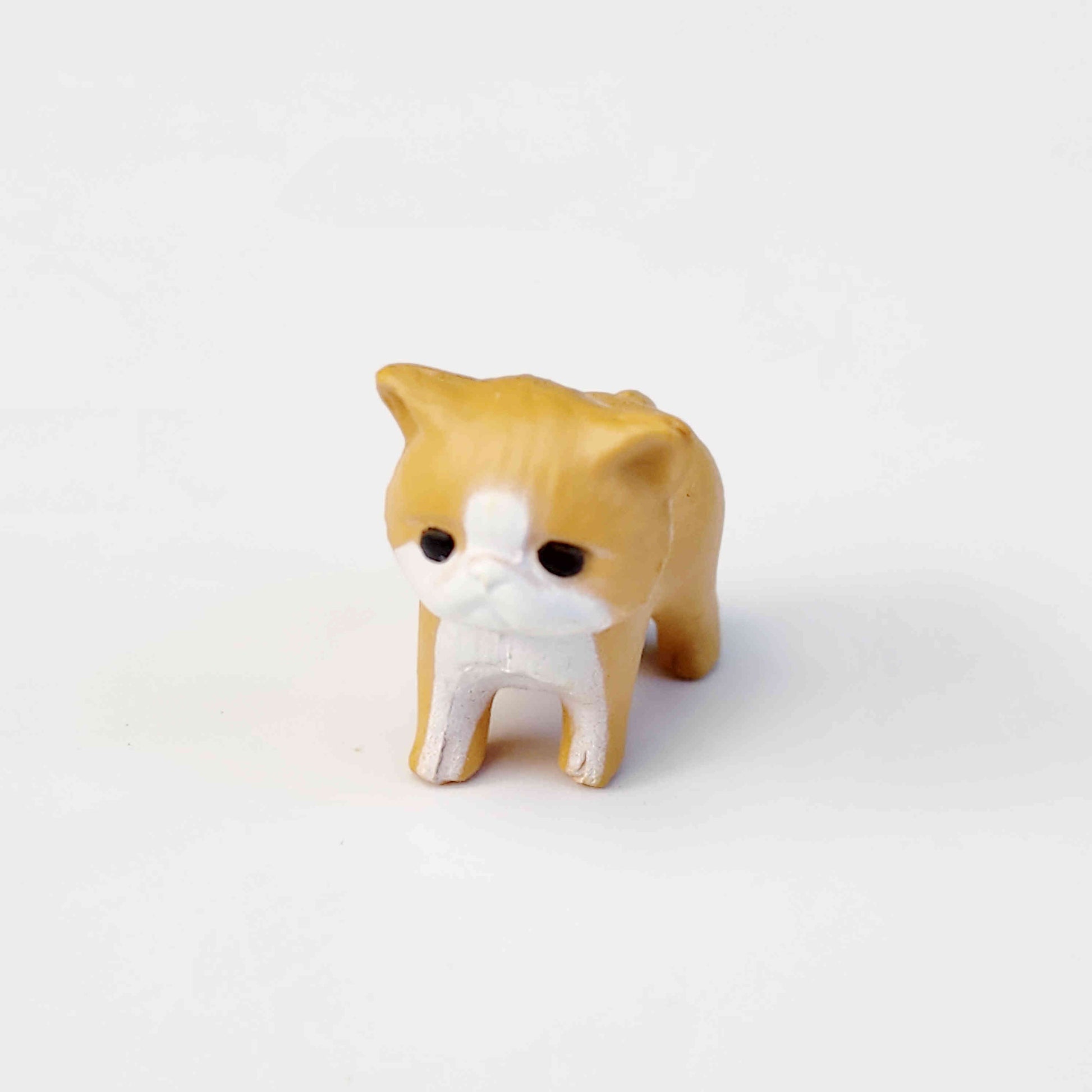 small ginger coloured PVC cat figurine on a white background
