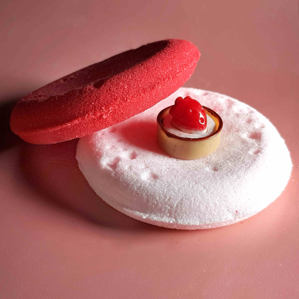 Flat disc shaped bath bomb stacked and placed on a plain pink background