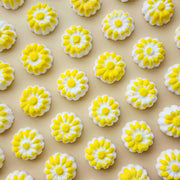 chamomile shaped mini bath bombs with a white base and yellow detail on a neutral plain background