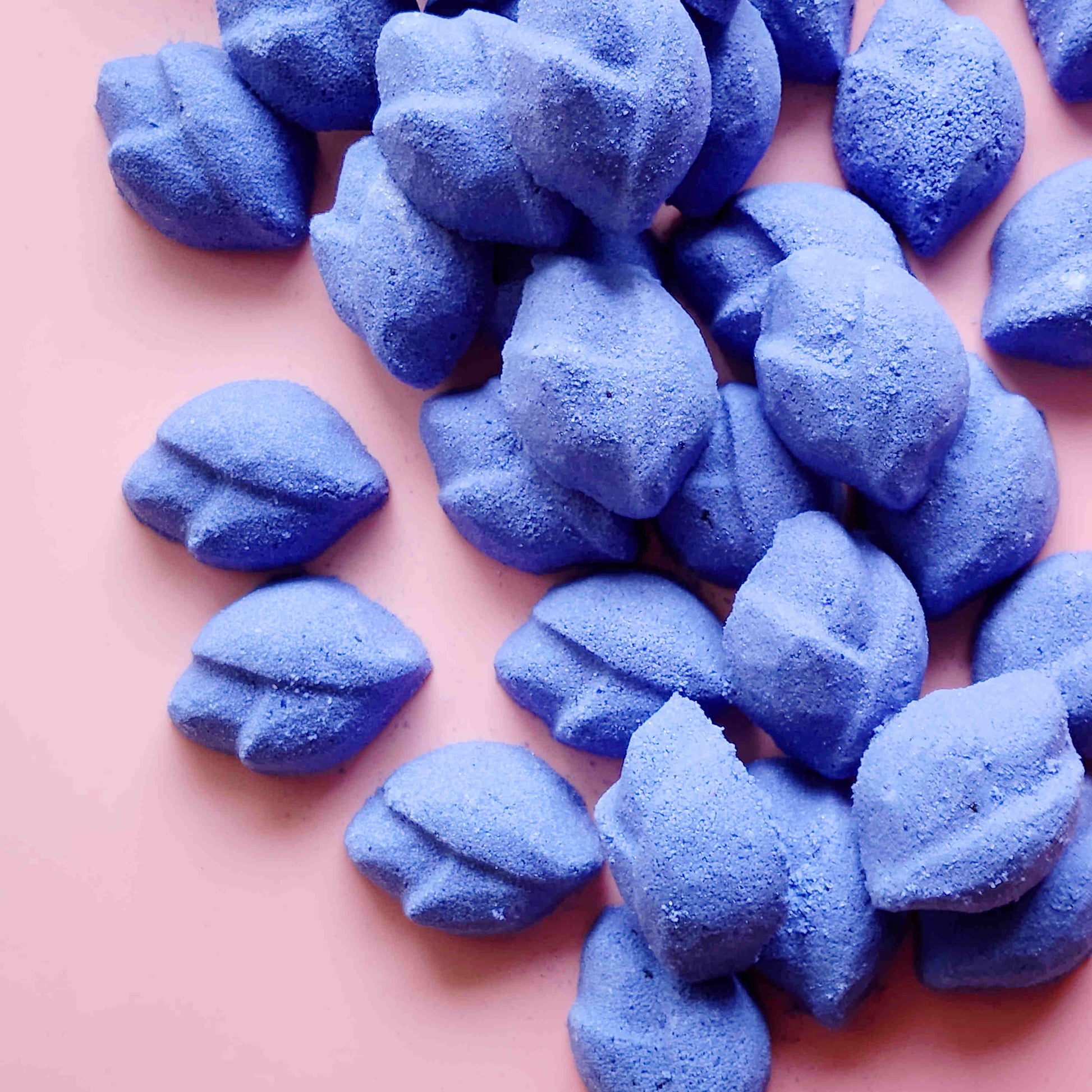 Pile of purple lip-shaped Lavender mini bath bombs on a pink background