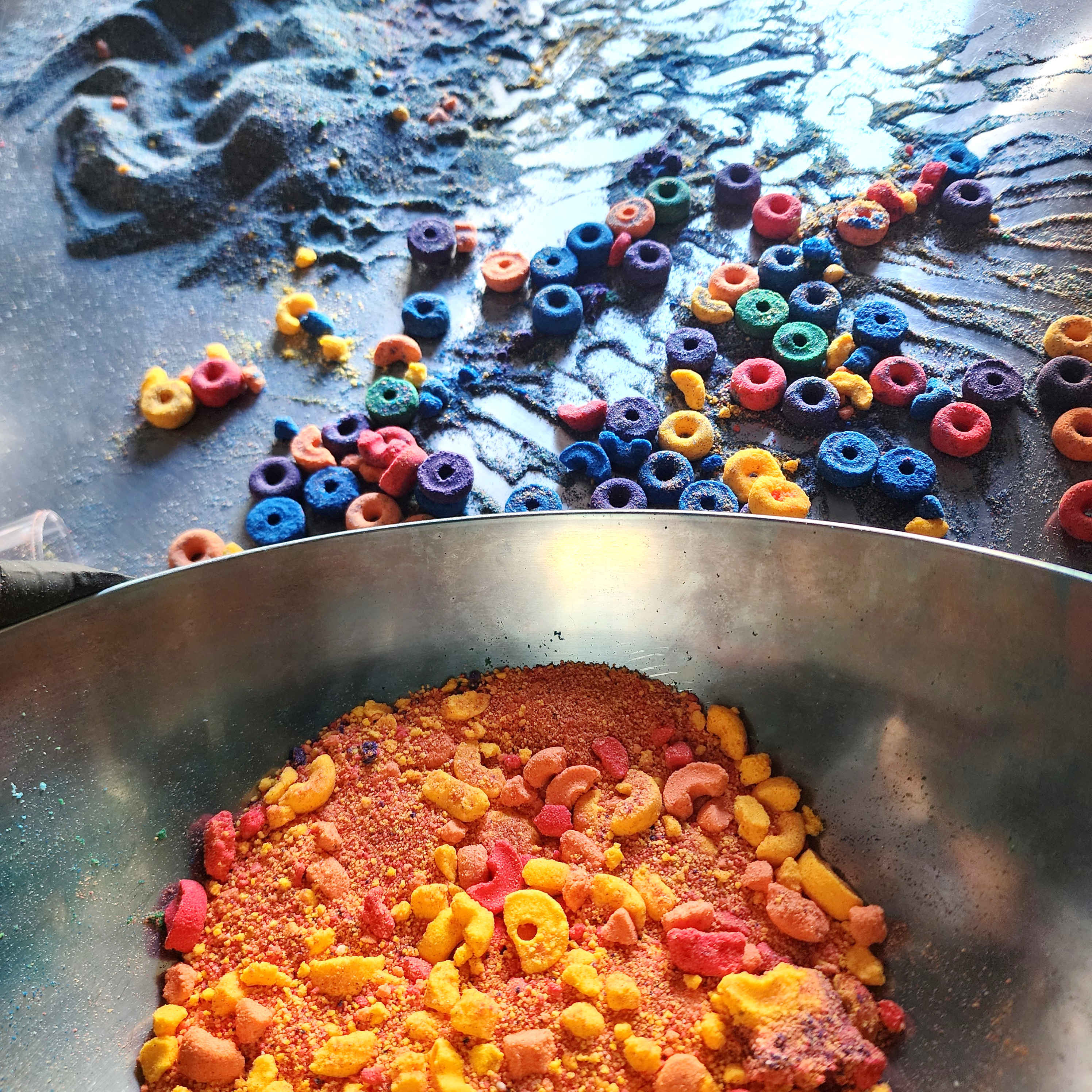 powdered bath bombs in a mixing bowl with fruit loop shaped bath bombs in the background