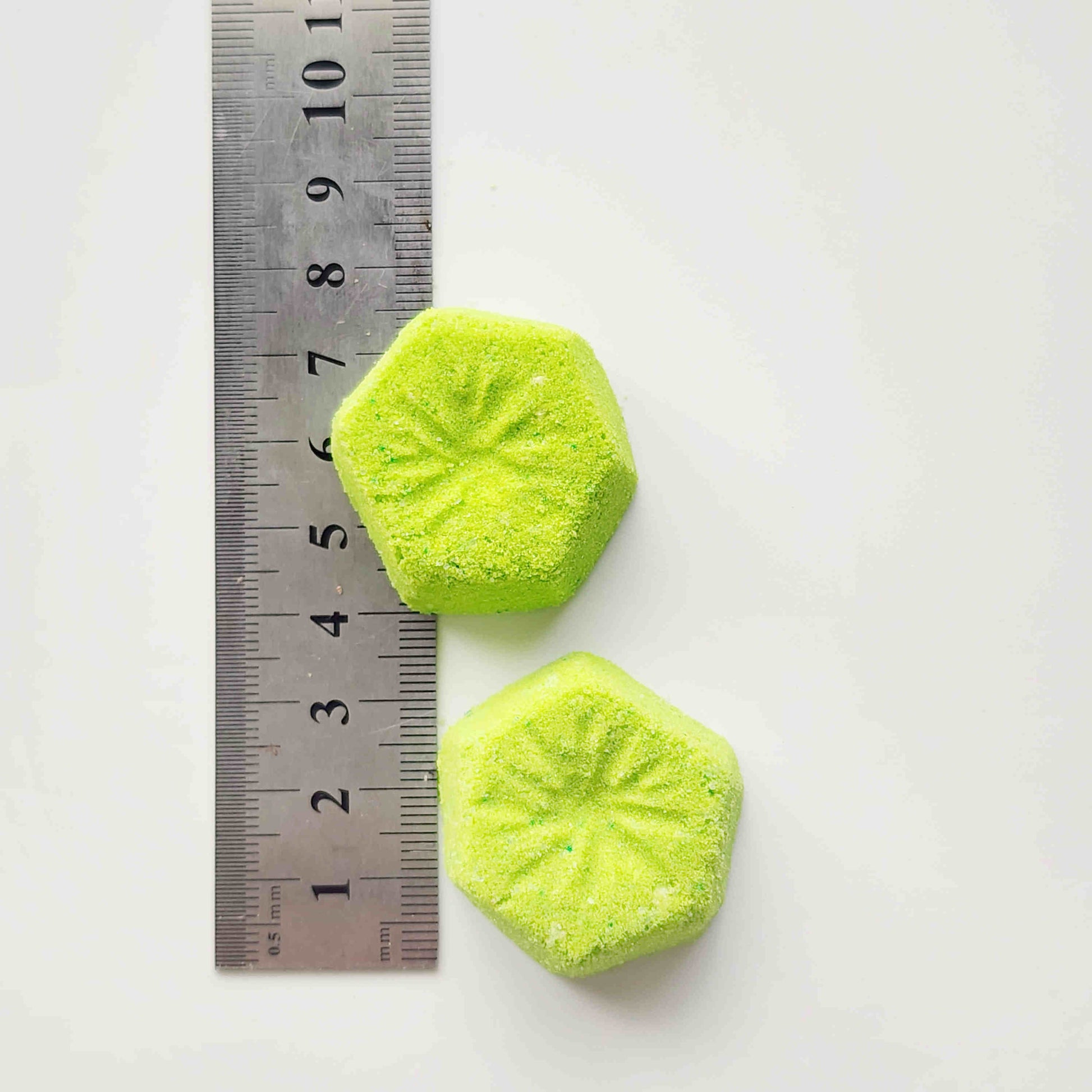 Two kiwi mini bath bombs measured beside a ruler