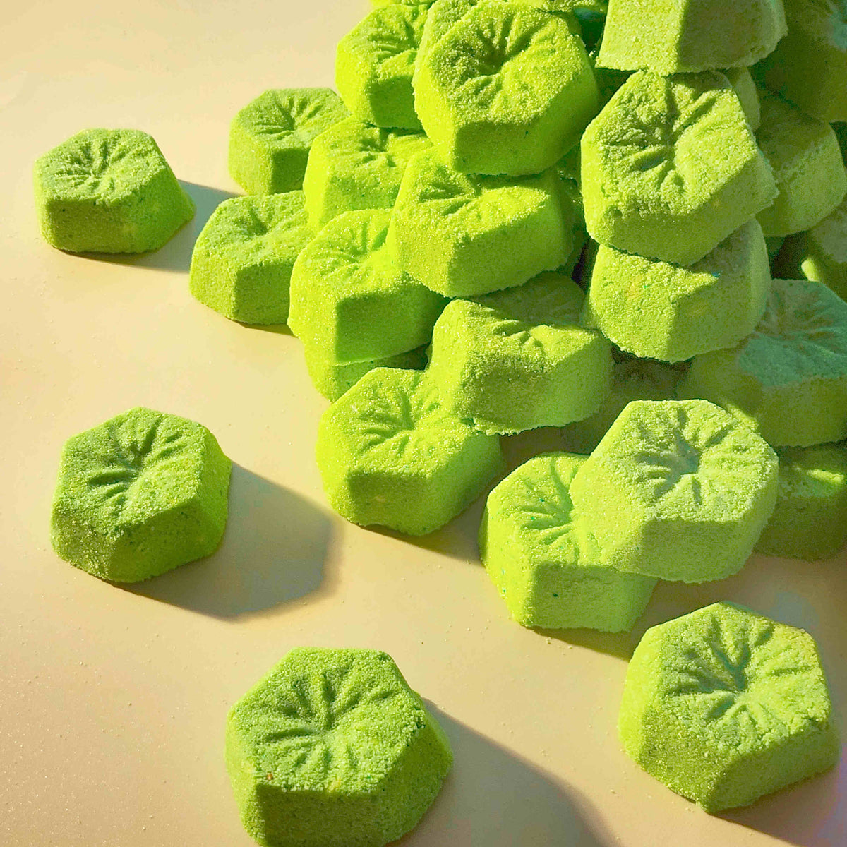 Pile of green kiwi mini bath bombs in warm sunlight
