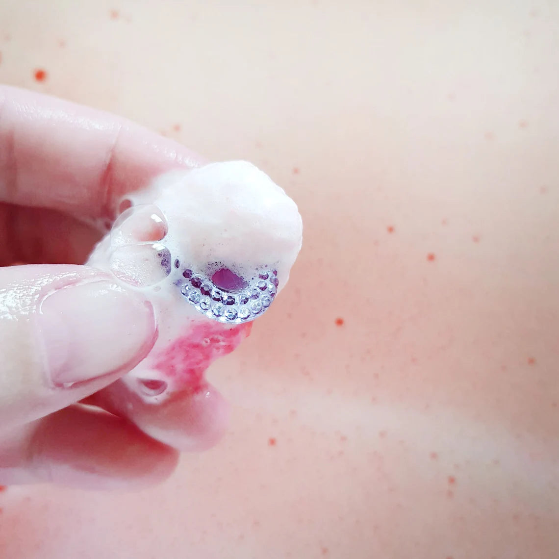 bejeweled toy ring being held over bath water covered in bubbles