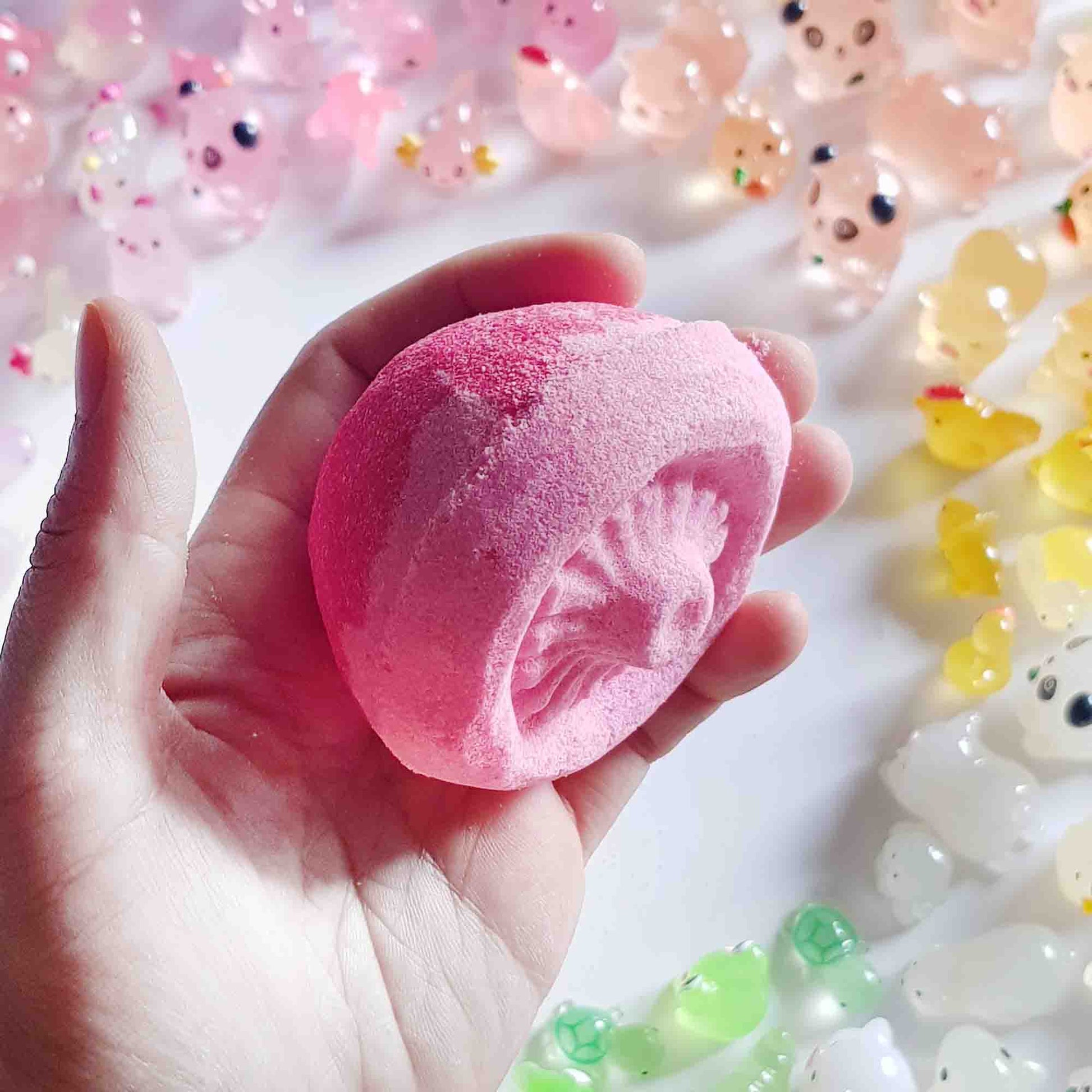 Hand holding a pink mushroom bath bomb to show its detailed underside