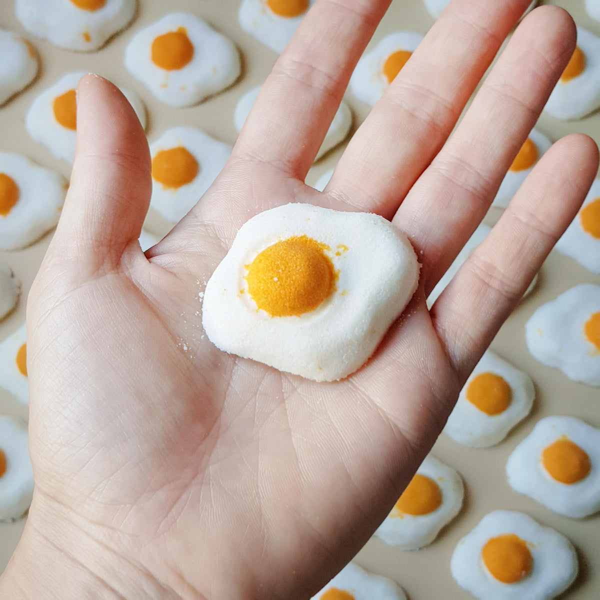 Mini sunny side up egg shaped bath bomb with a golden orange yolk