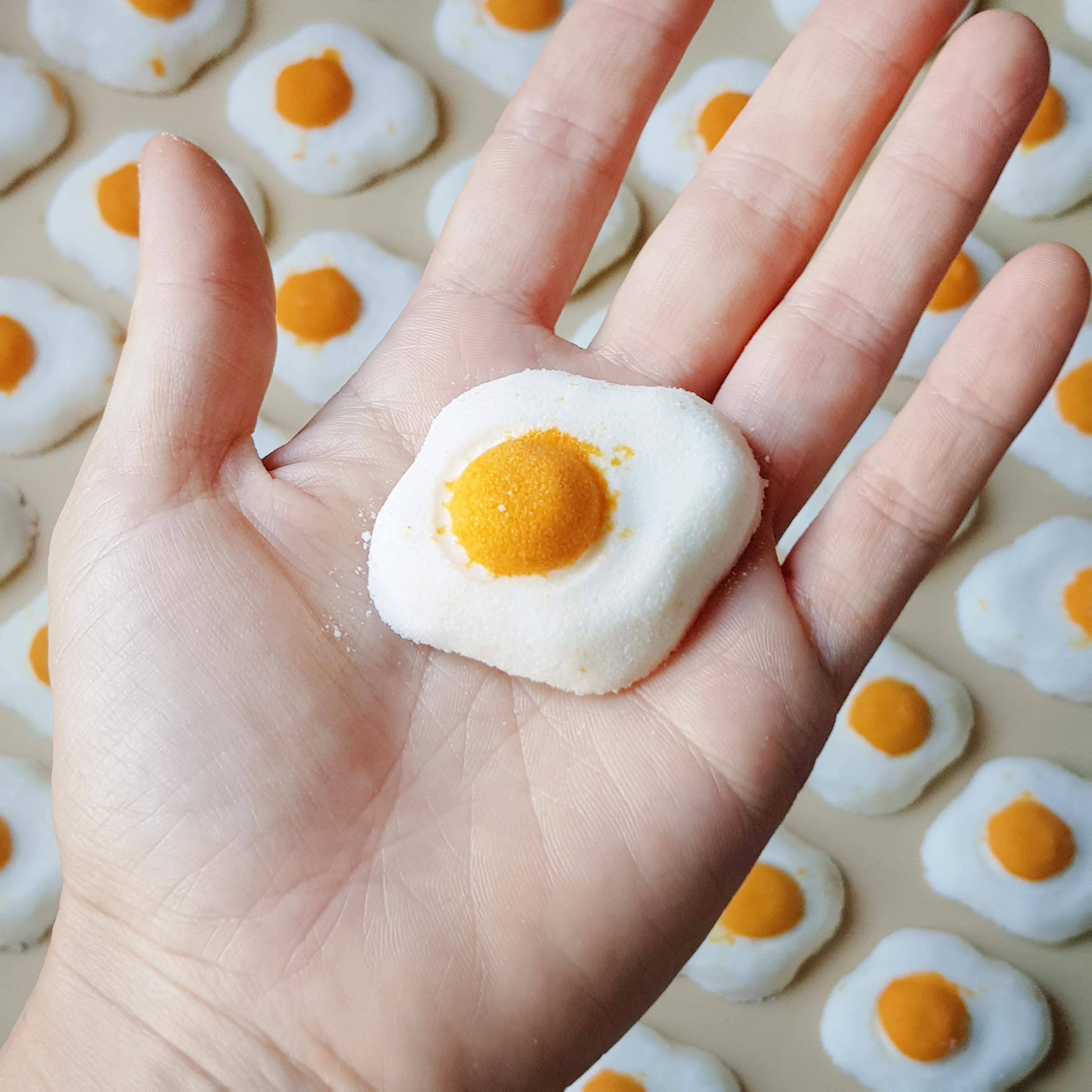 Mini sunny side up egg shaped bath bomb with a golden orange yolk