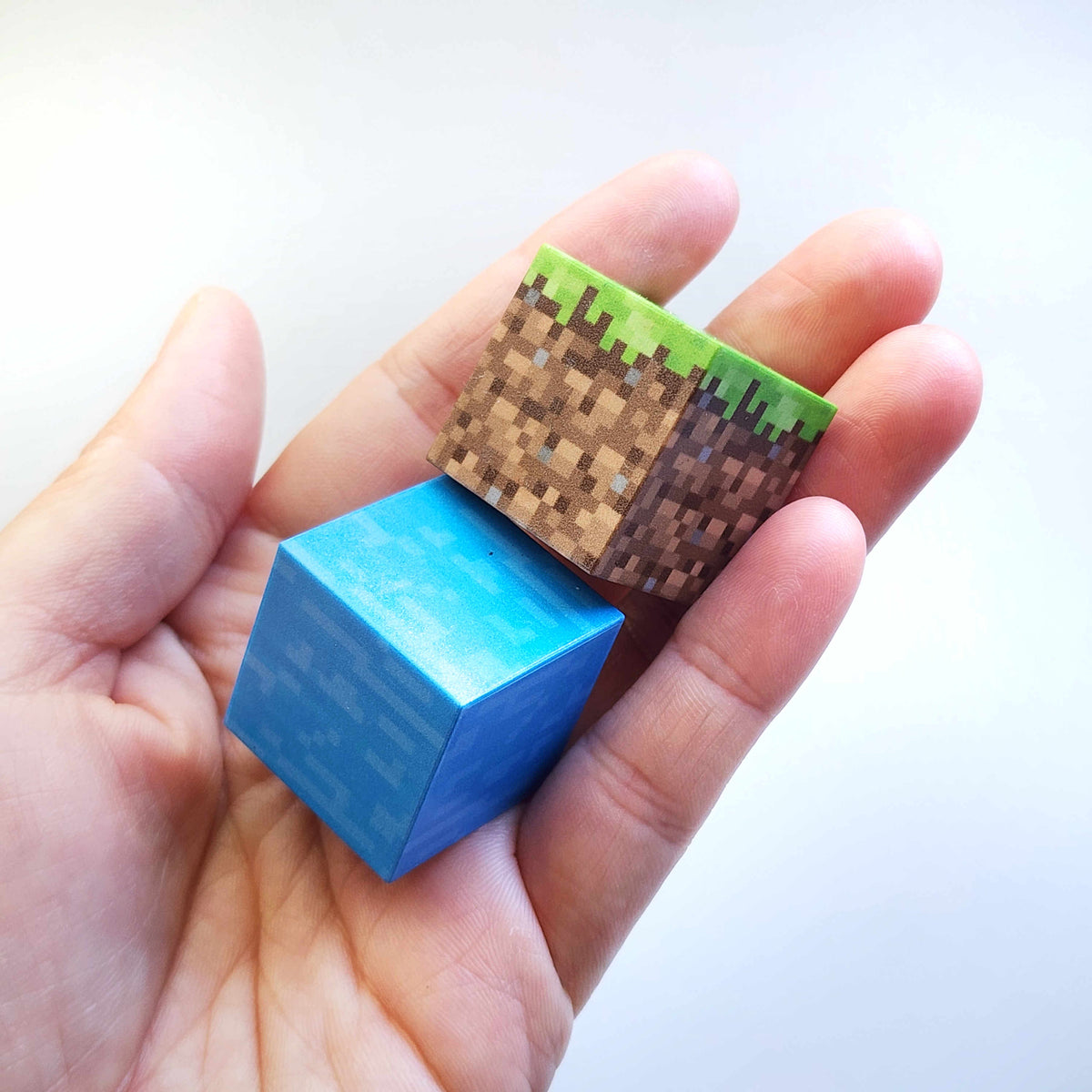 Hand holding grass and water Minecraft-style magnetic building blocks