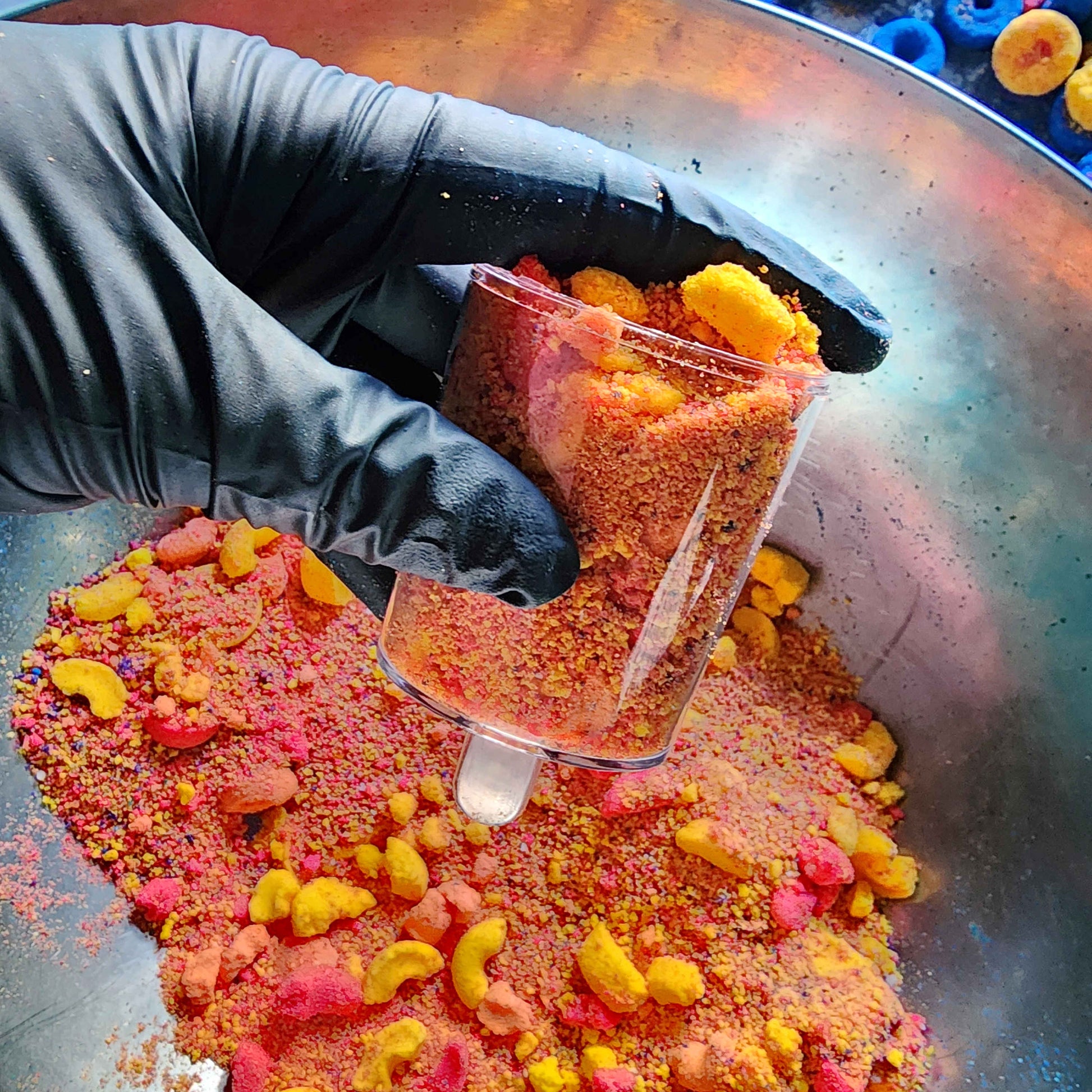 powdered bath bombs in a mixing bowl with fruit loop shaped bath bombs in the background