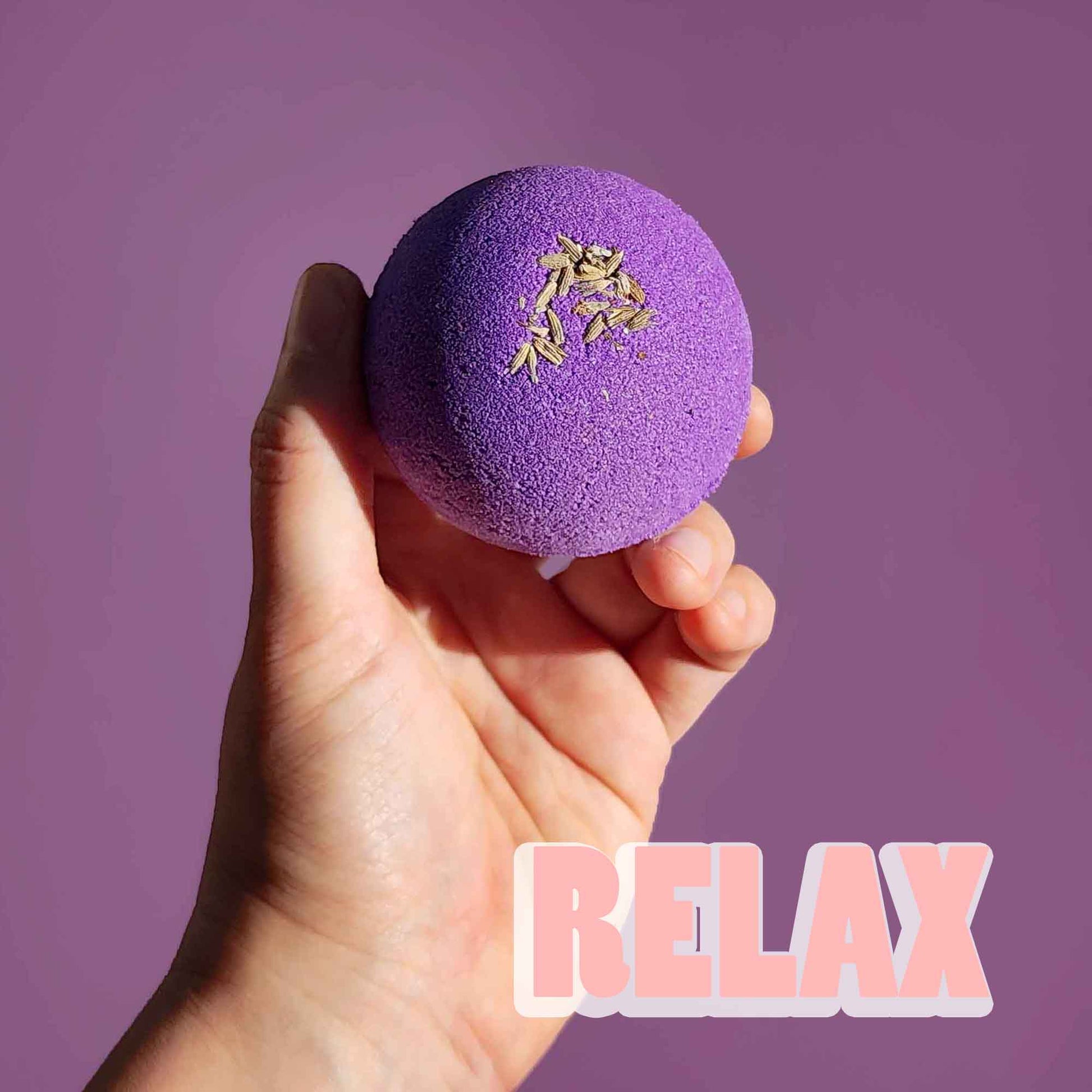 Hand holding the purple Relax aromatherapy bath bomb