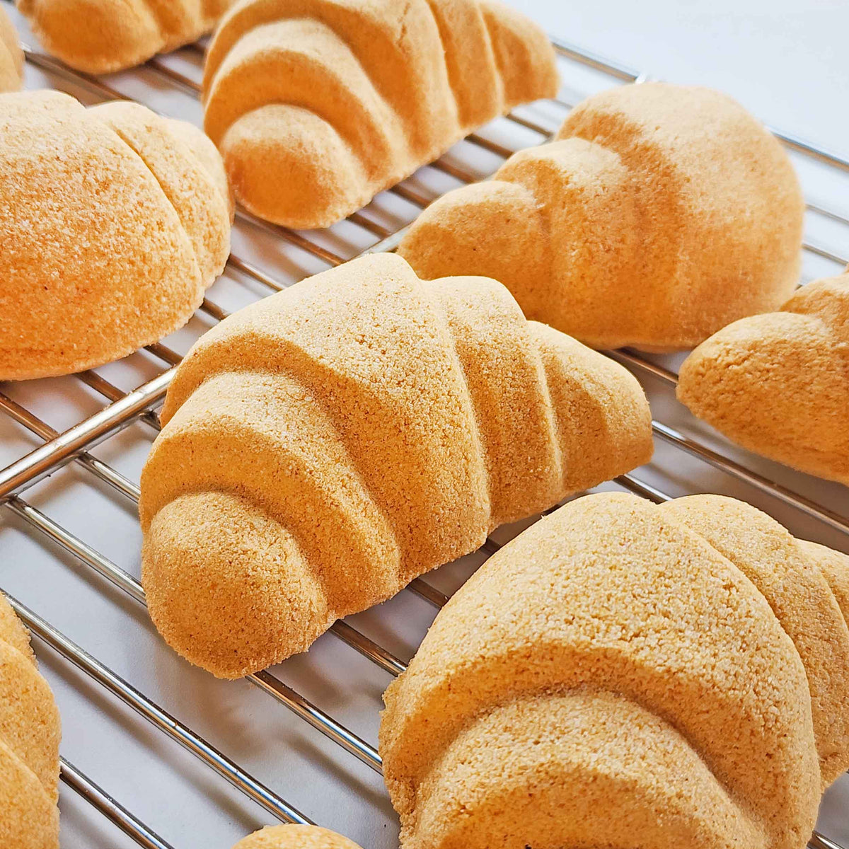 Croissant and bread-loaf bath bombs cooling together on a rack