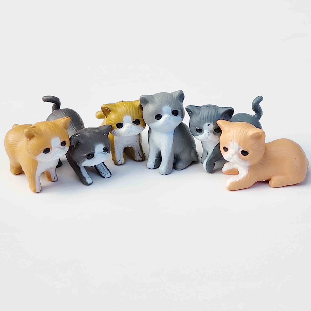 Half circle of small PVC cat figurines on a white background
