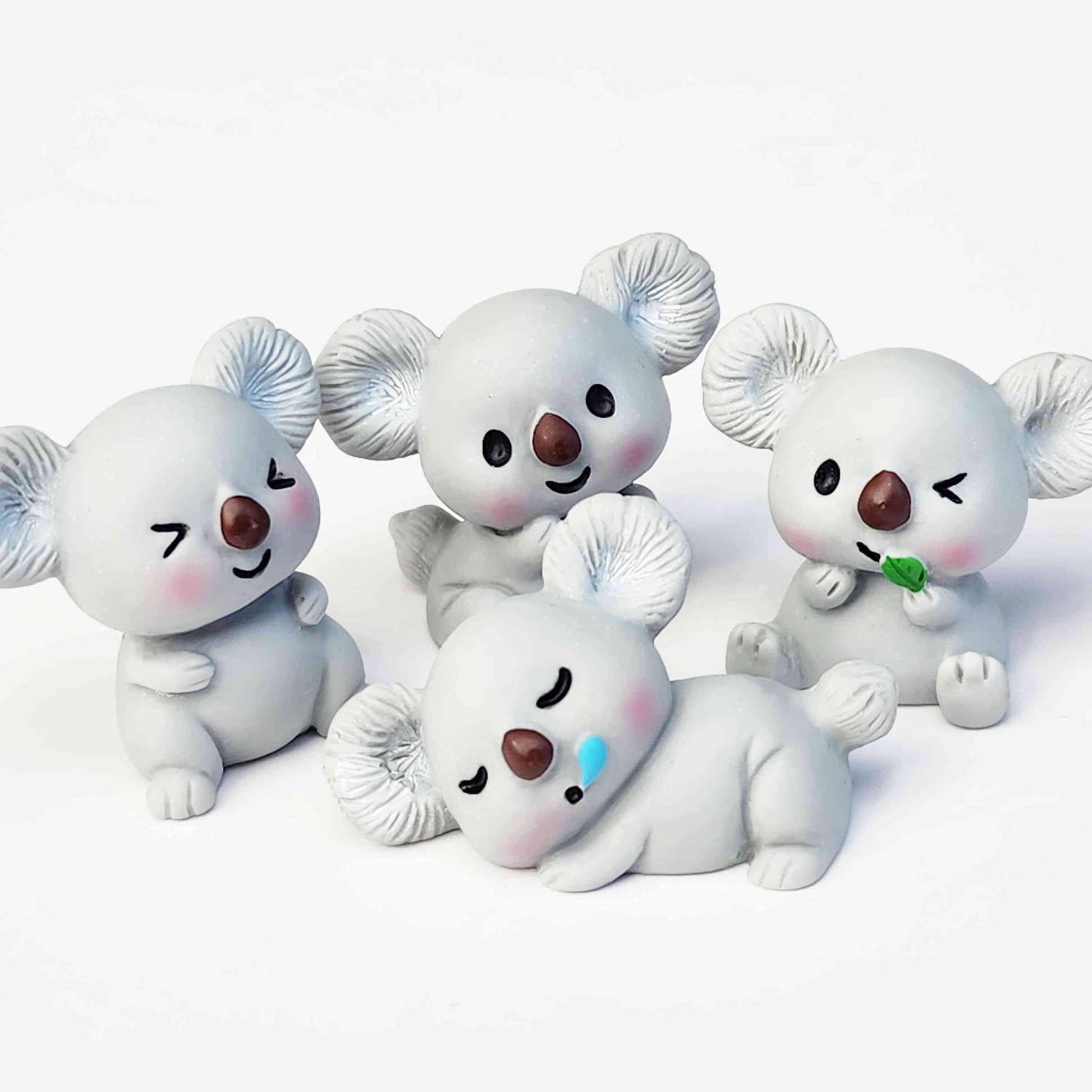 Cute grey koala resin figurines on a white background