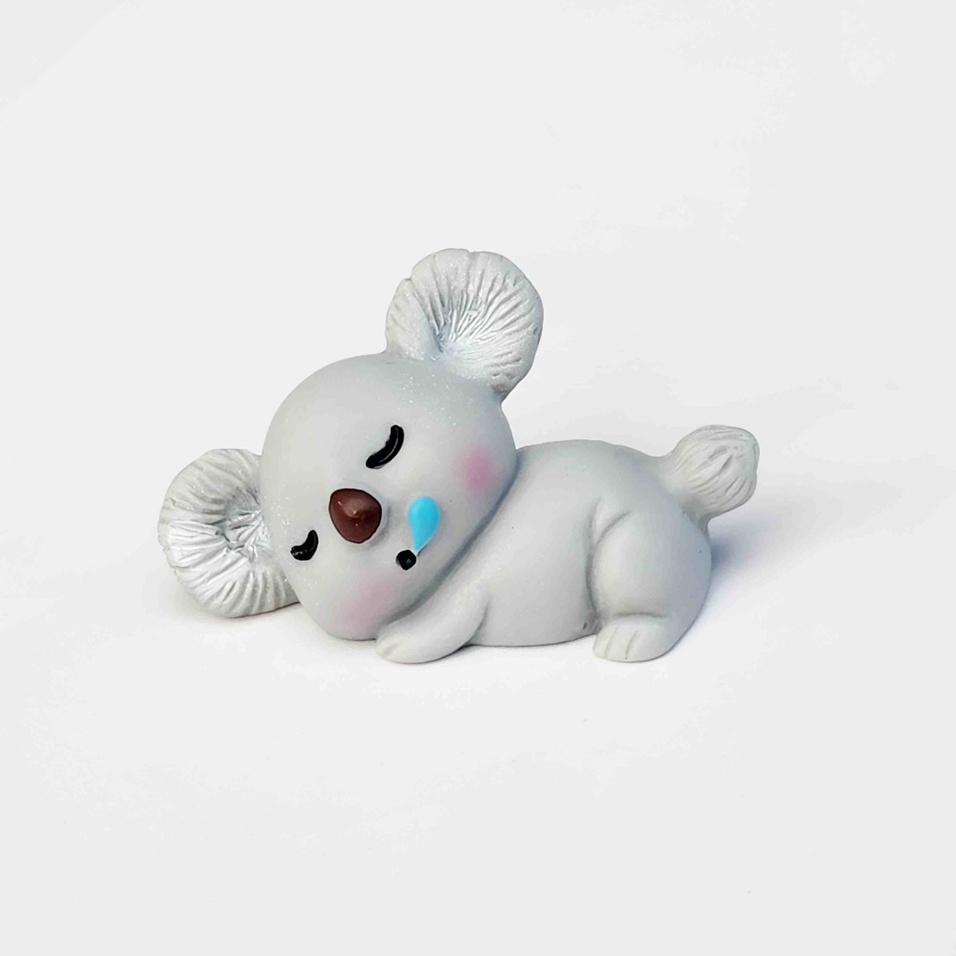Sleeping grey koala figurine on a white background