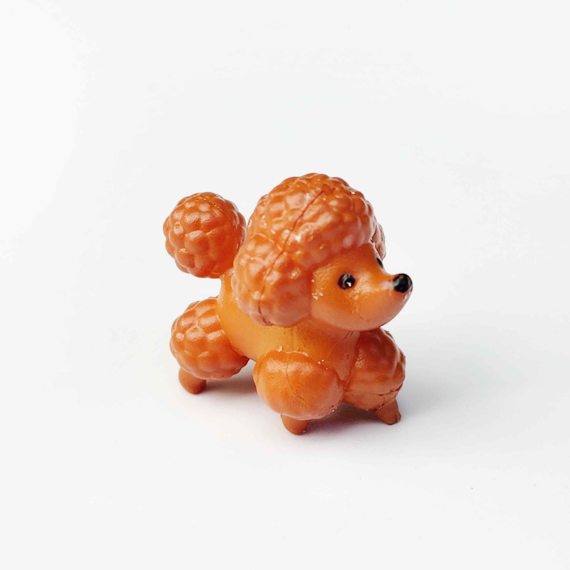 Chocolate poodle pvc figurine on a plain white background