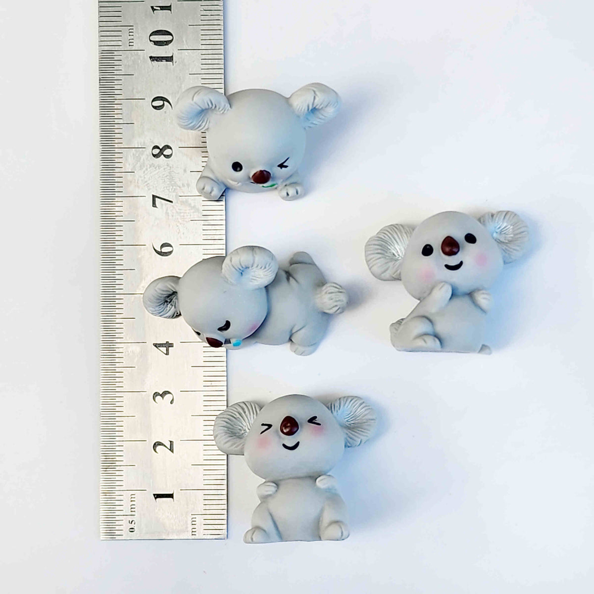 measurements for four grey koala figurines laid out on a white background
