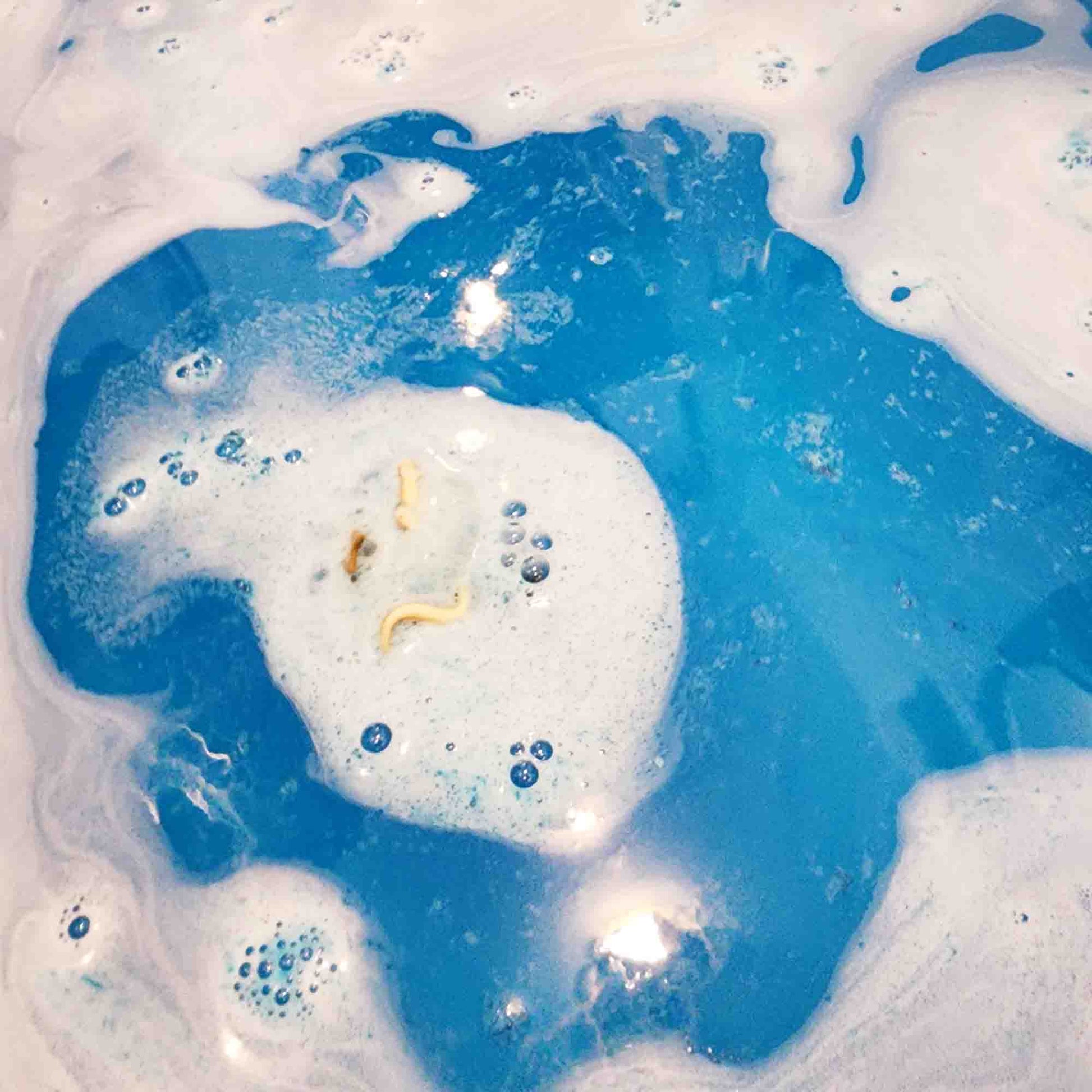 teal blue bath bomb dissolving in a bath turning the water a lush blue